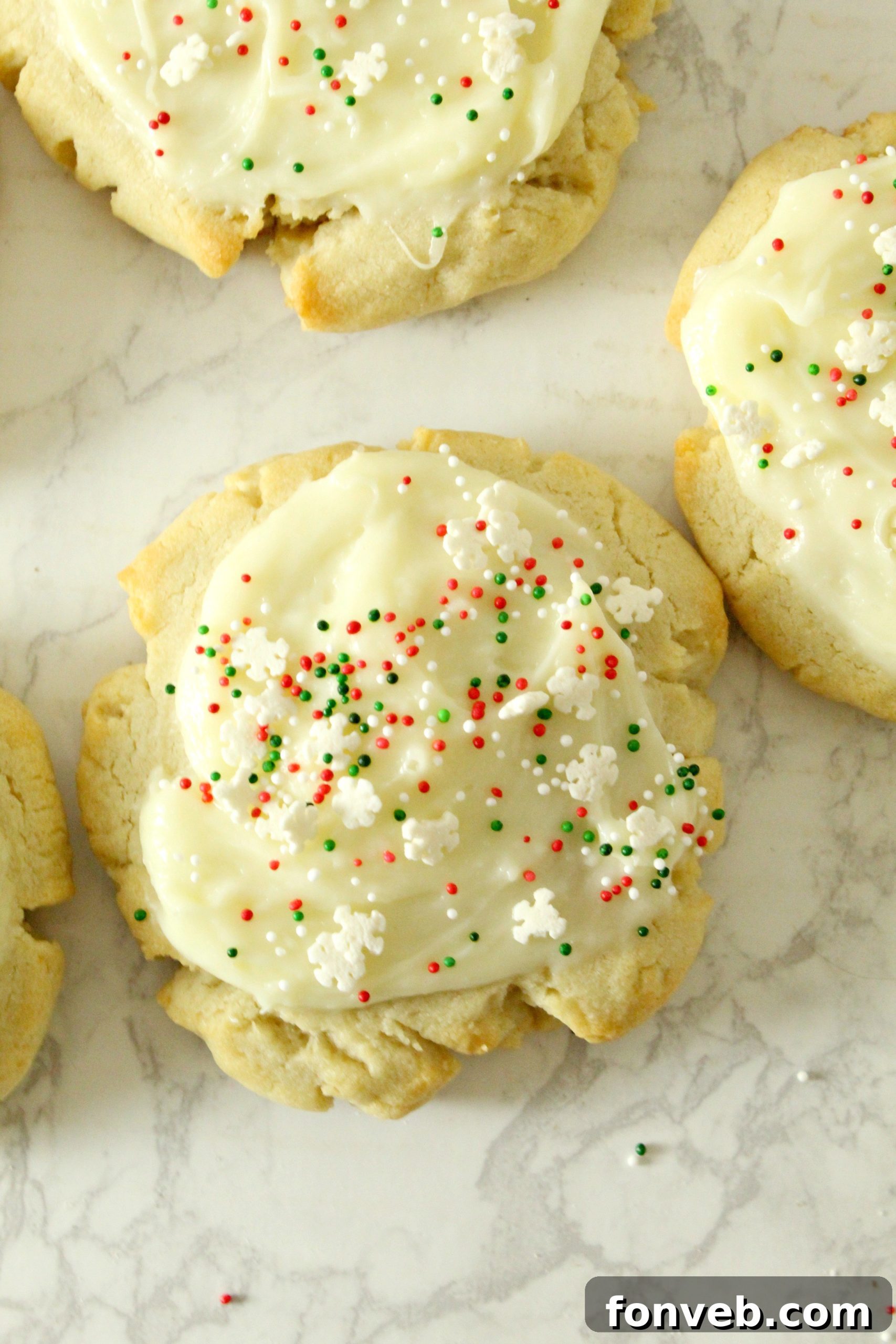 A close-up of a hand sprinkling colorful decorations onto a frosted Swig Sugar Cookie.