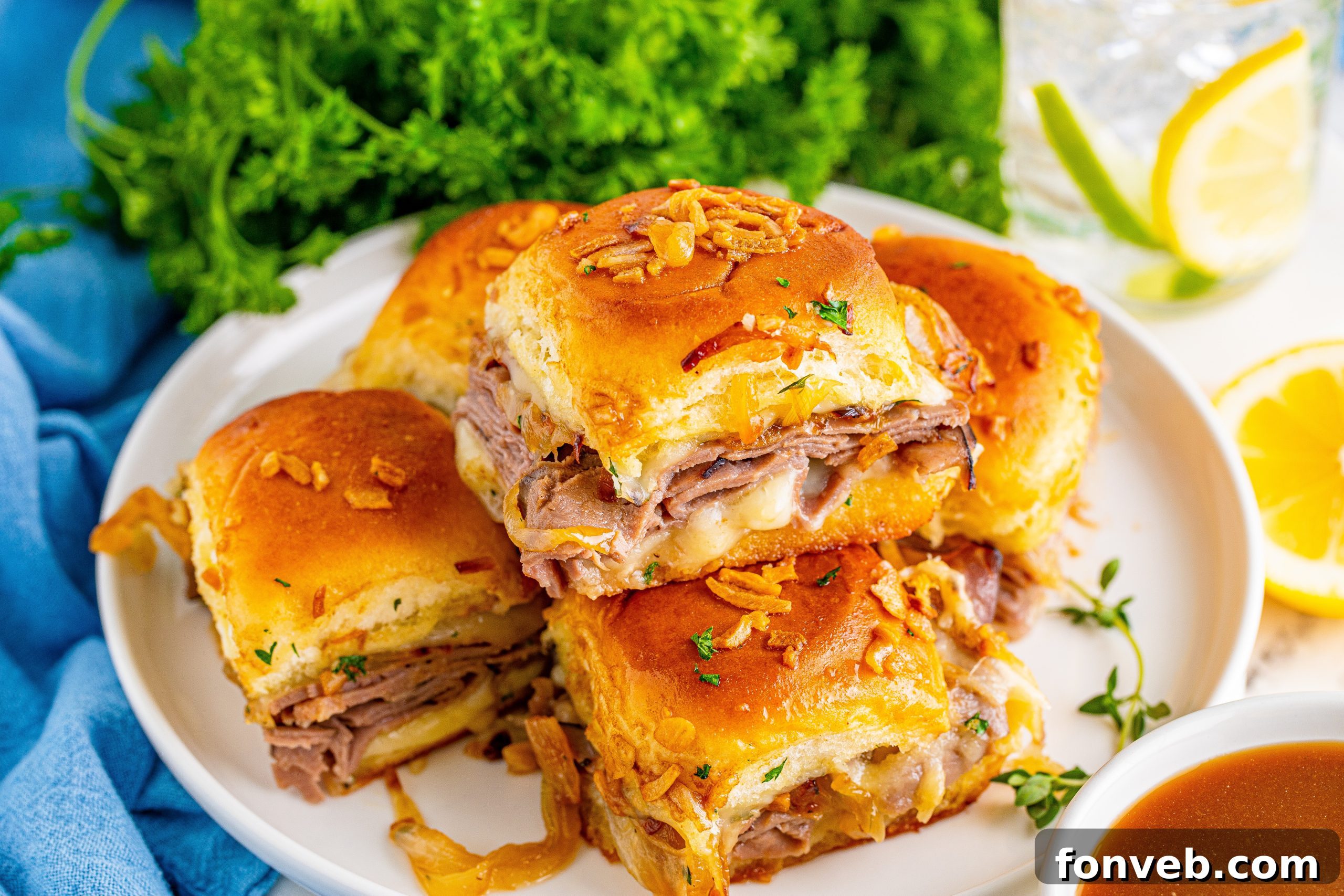 Dunkable French Dip Sliders 5 French Dip Sliders piled on a white plate with a blue napkin