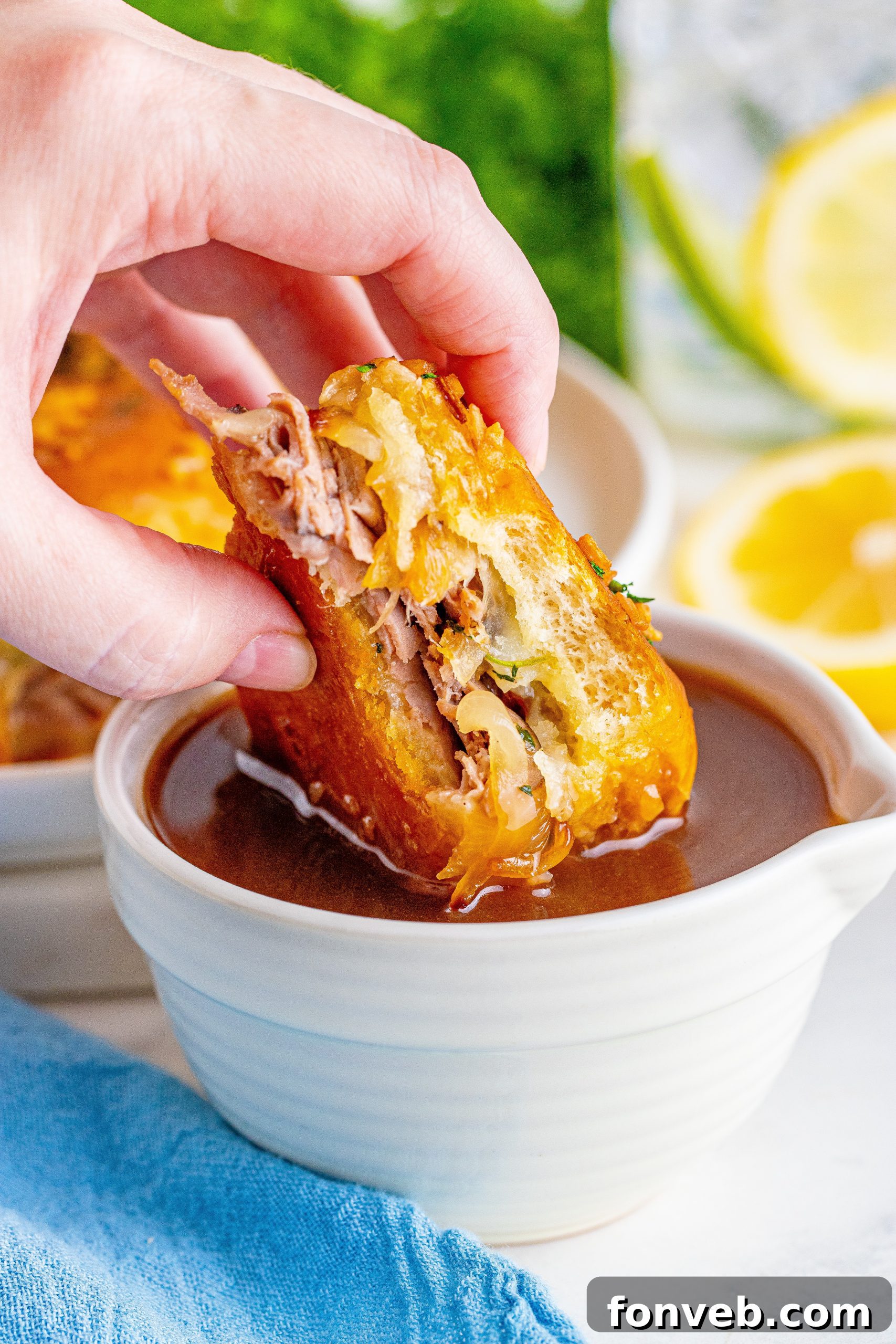 Dunkable French Dip Sliders 6 French Dip Sliders being dipped into a white bowl of Au Jus