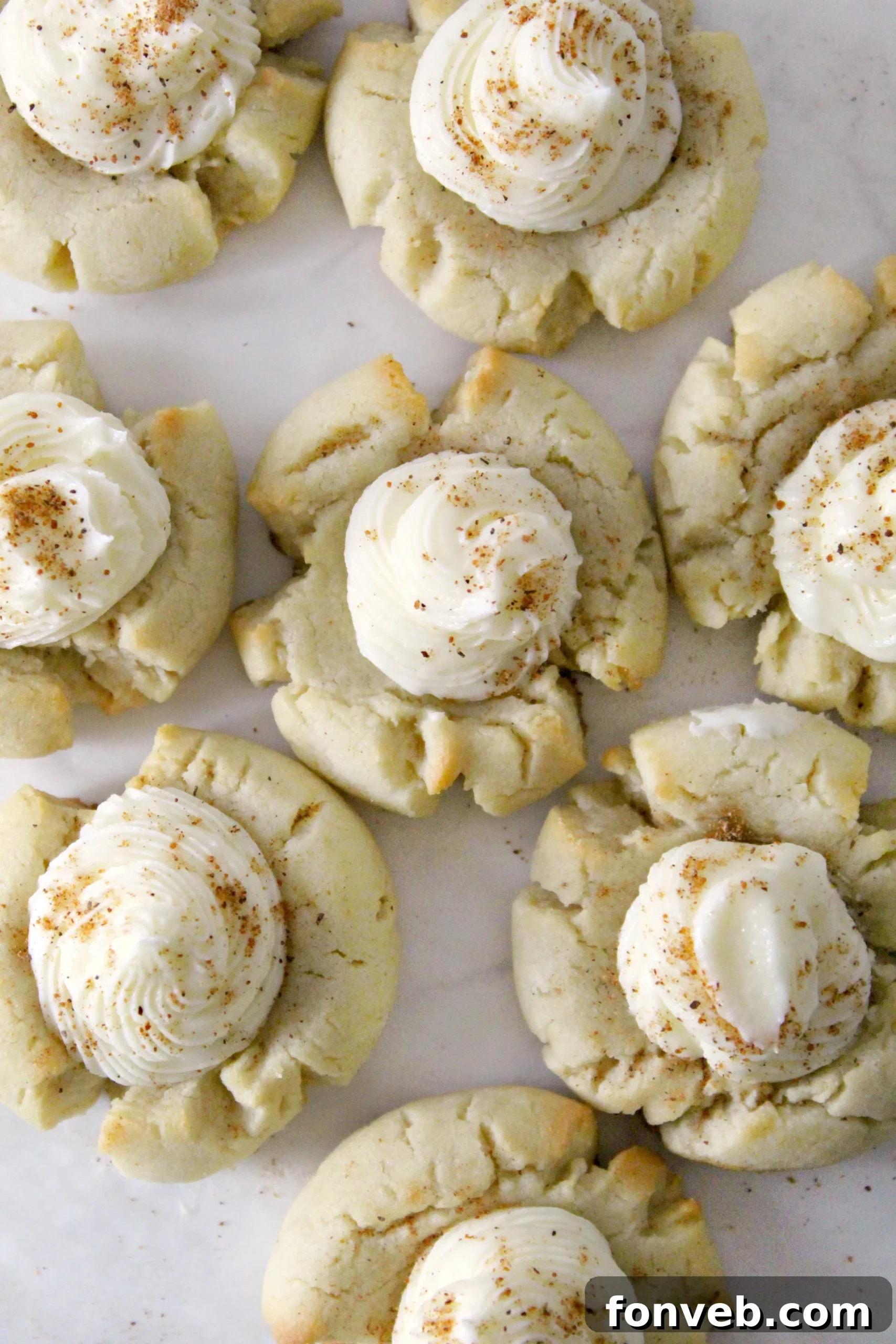 Close-up of freshly baked Eggnog Thumbprint Cookies with rum frosting, garnished with nutmeg.