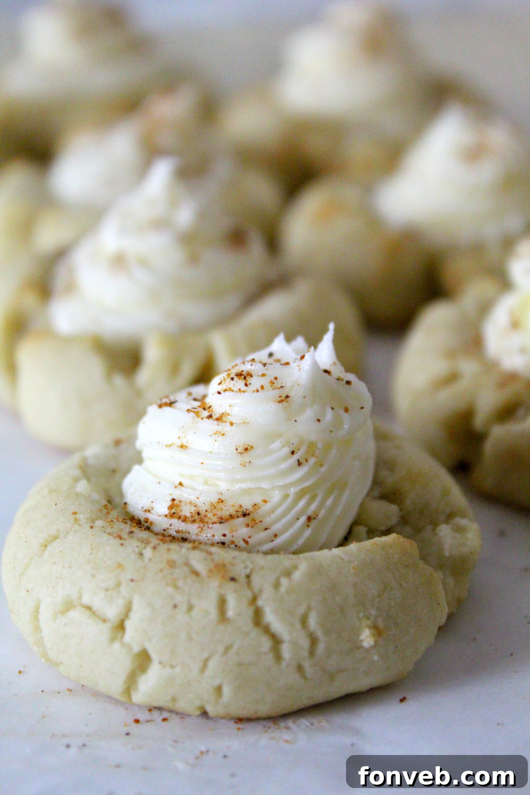 Stack of Eggnog Thumbprint Cookies on a festive plate, showing their soft texture and creamy frosting.