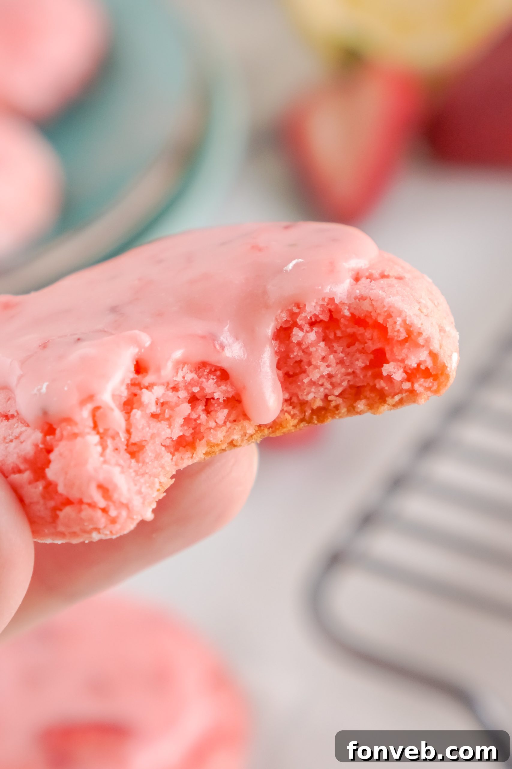 Top-down view of a single glazed strawberry cookie on a wooden surface.