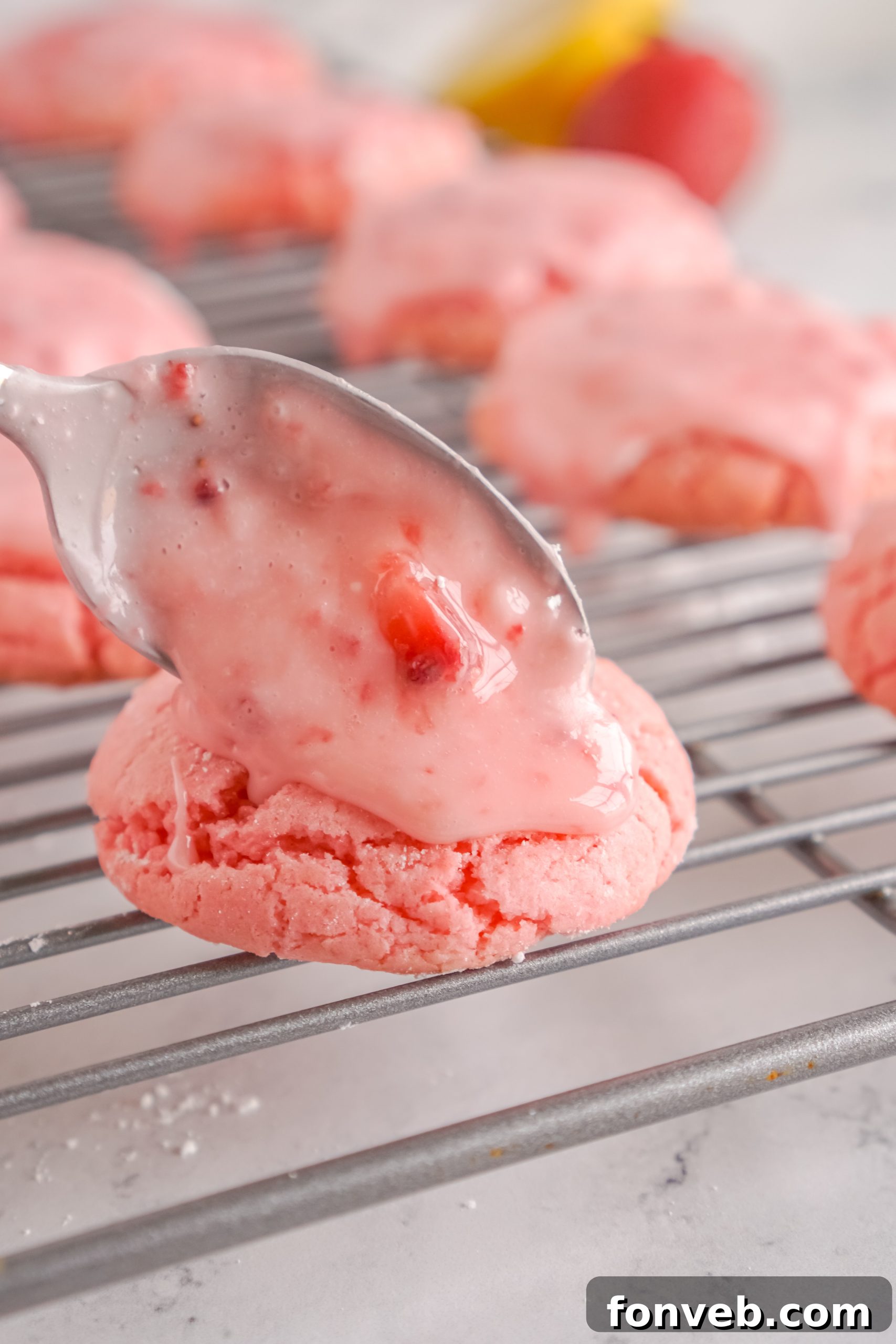 Stack of glazed strawberry cookies with a fresh strawberry on top, on a white plate.