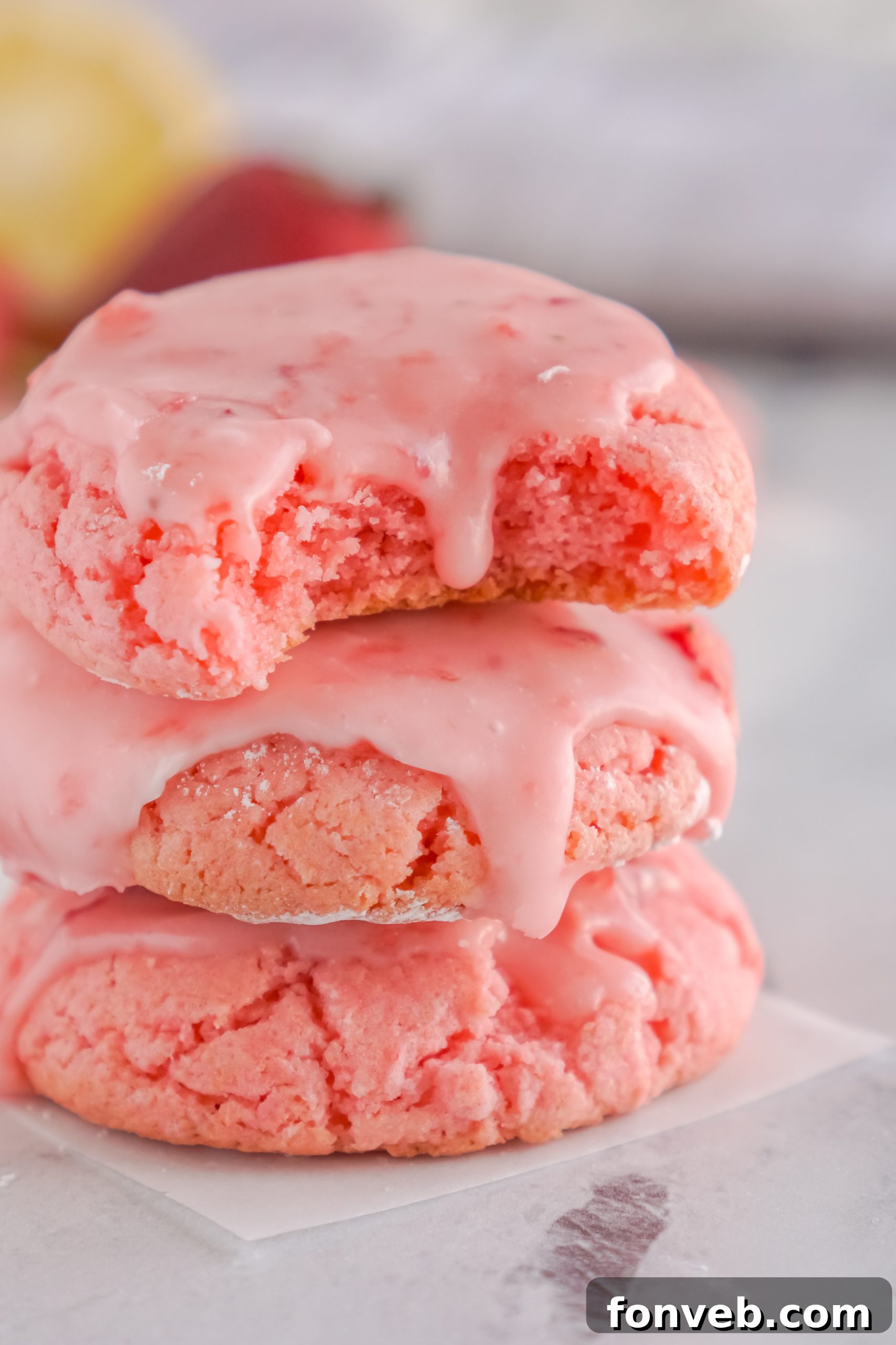 Batch of glazed strawberry cookies cooling on a wire rack.