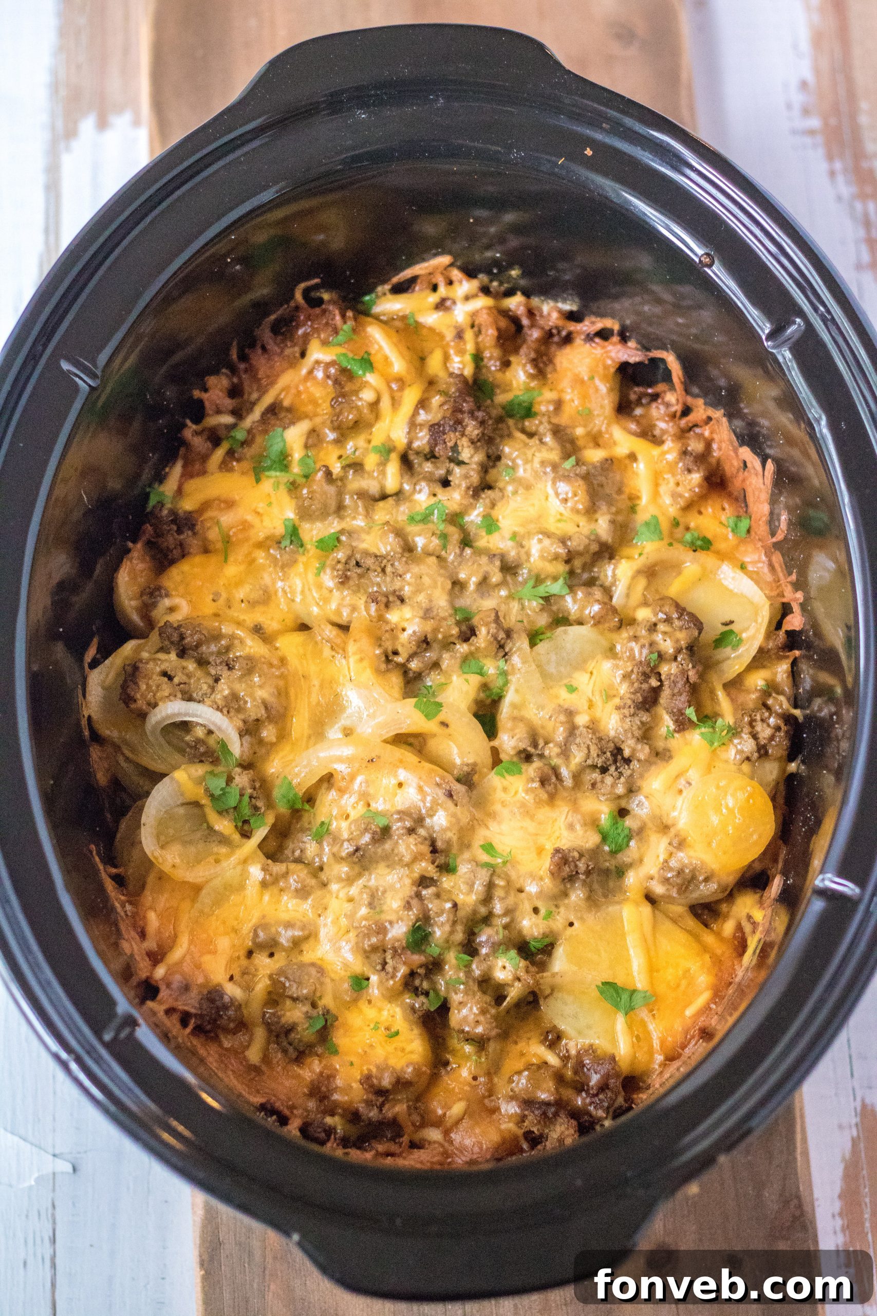 Freshly sliced potatoes arranged in a slow cooker, ready for the next layers of ingredients.