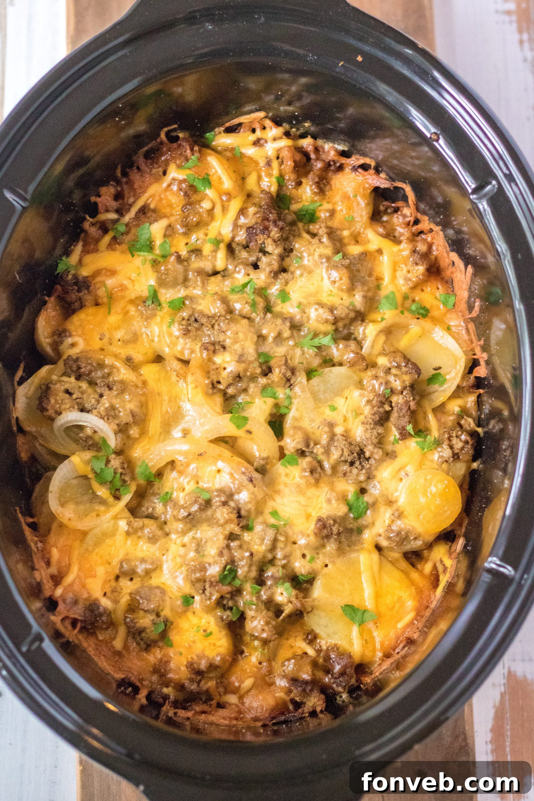 Overhead shot of Slow Cooker Beef and Potato Au Gratin in the slow cooker, ready to be served, highlighting its rich, golden-brown top.