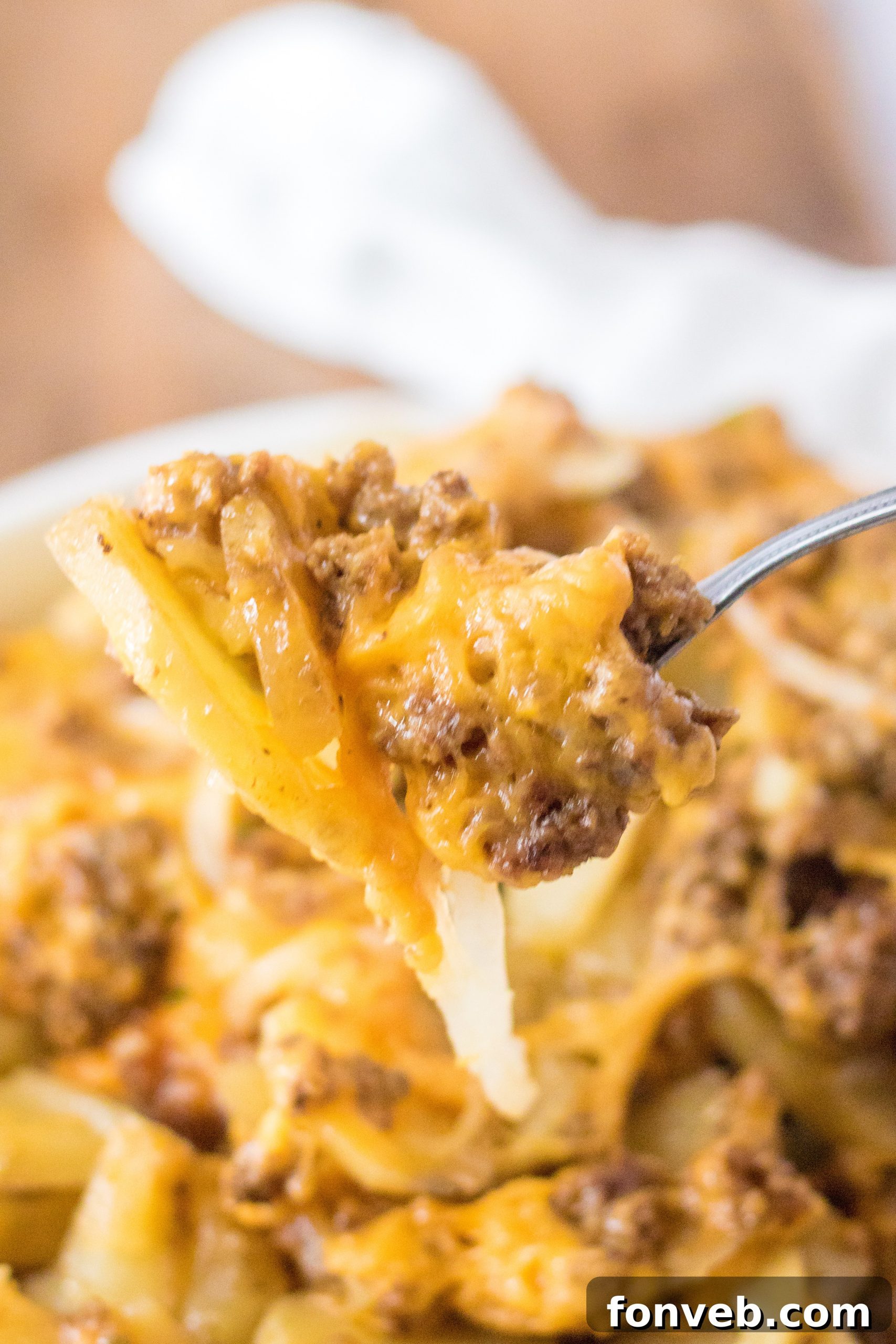 Serving spoons dishing out the Slow Cooker Beef and Potato Au Gratin, showing the moist and layered texture.