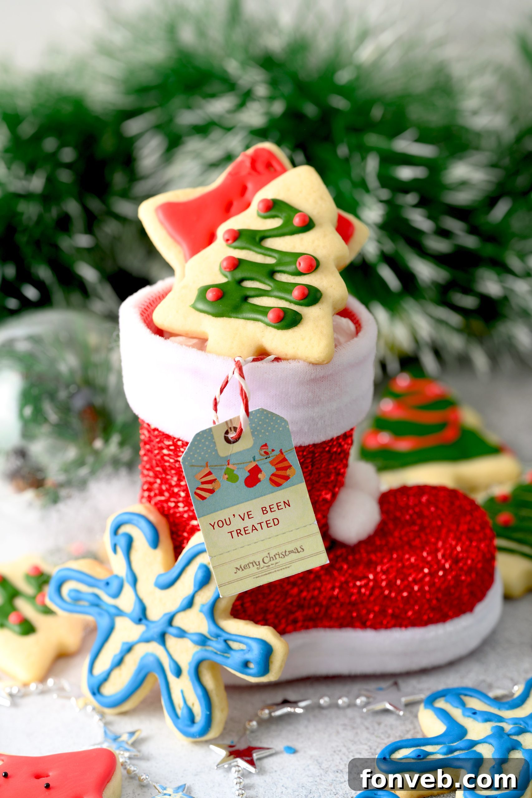 A baker's hands arranging a tray of sugar cookies fresh from the oven, with a final decorated cookie in the foreground.