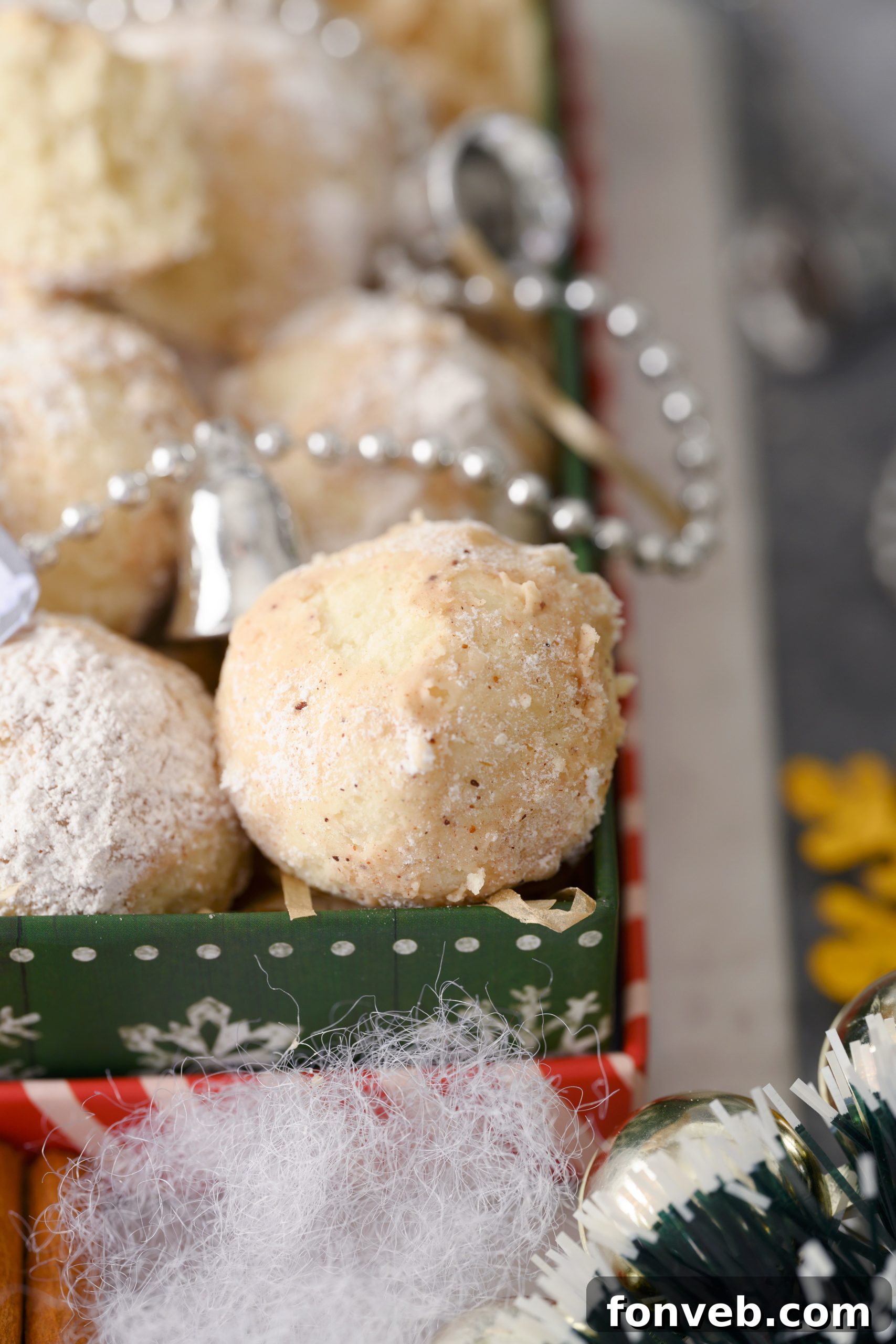 A hand reaching for a Cinnamon Mexican Wedding Cookie from a tray