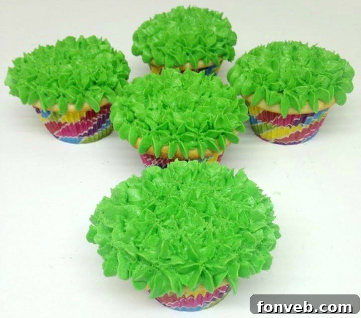 A cluster of beautifully decorated Easter bunny butt cupcakes with green frosting and colorful eggs.