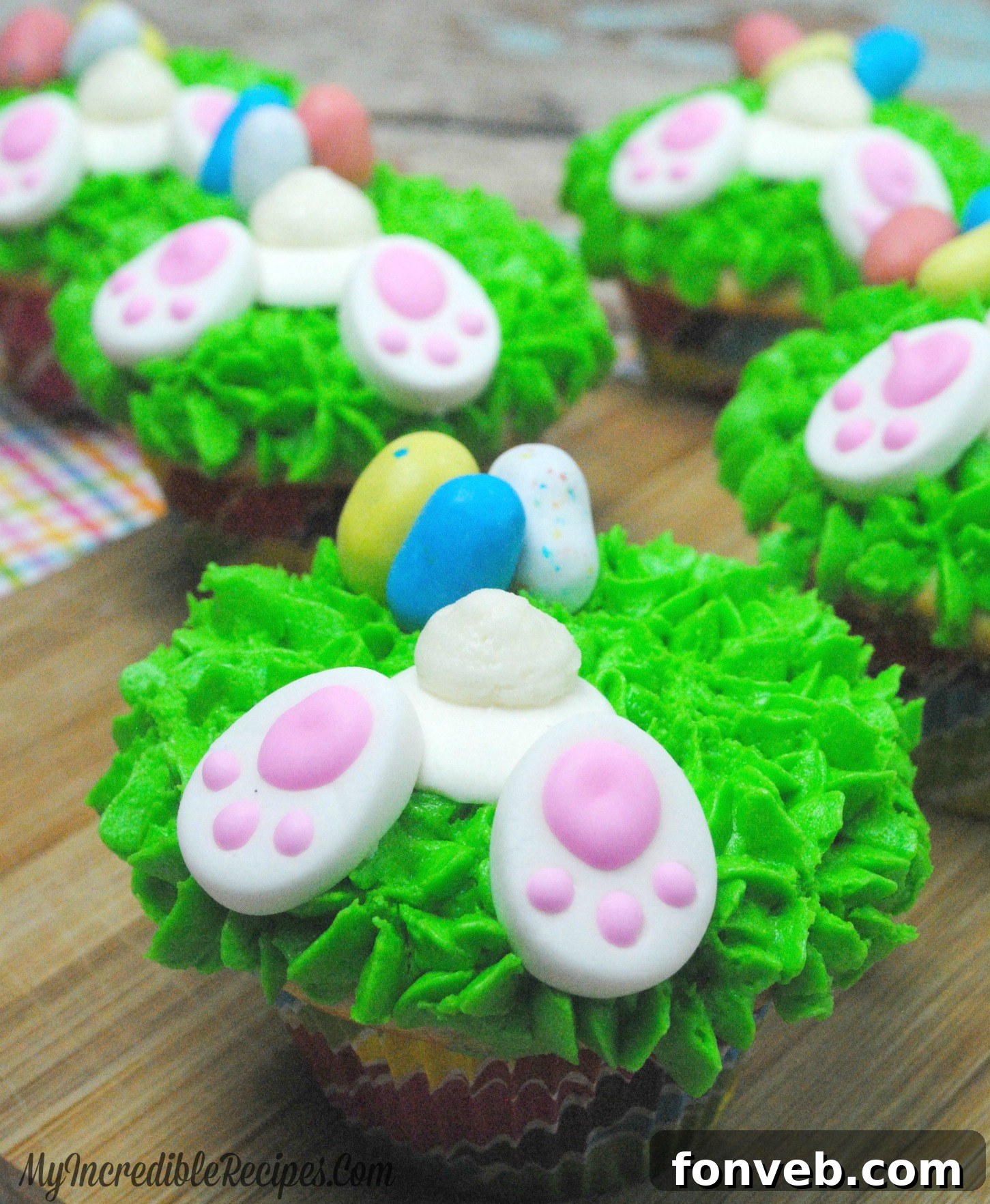 Overhead view of multiple Easter bunny bum cupcakes and scattered mini chocolate eggs.