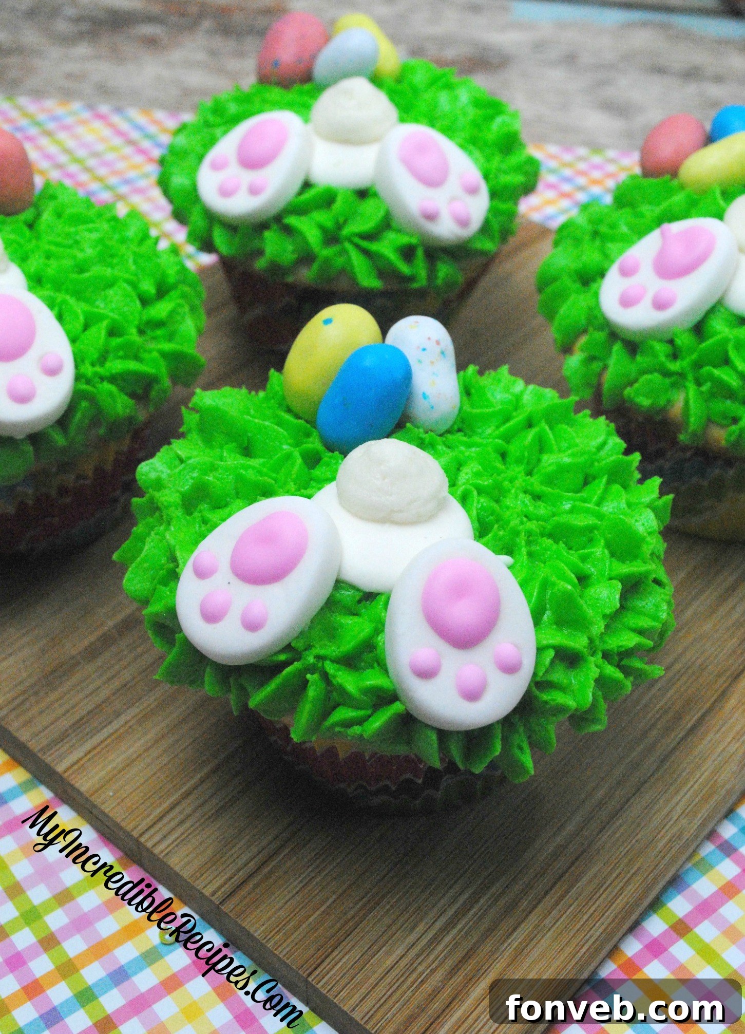 Close-up of Easter cupcakes adorned with green frosting and small, colorful malted eggs.
