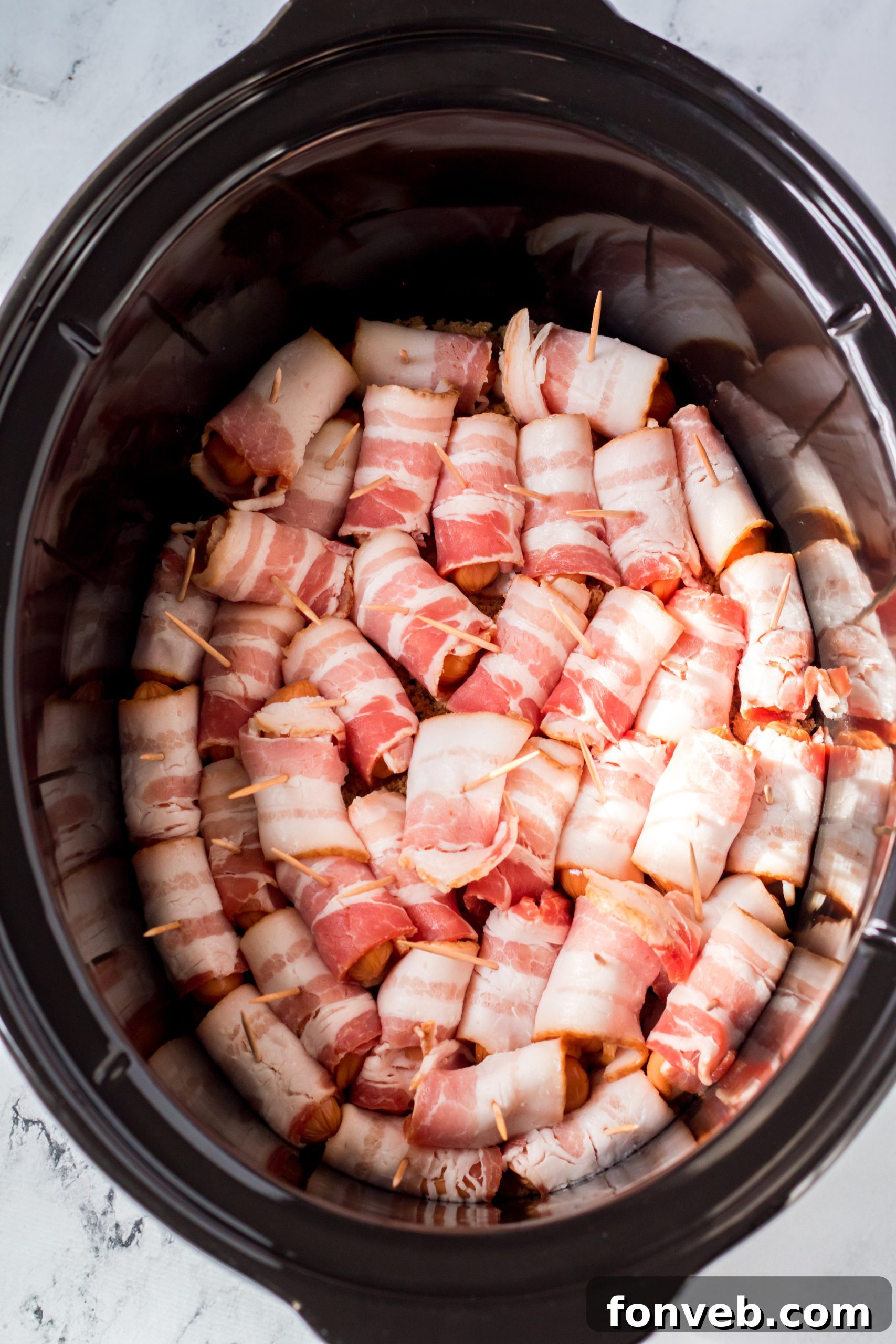Slow Cooker Bacon Wrapped Smokies with a hint of spice, garnished with a sprinkle of seasoning.