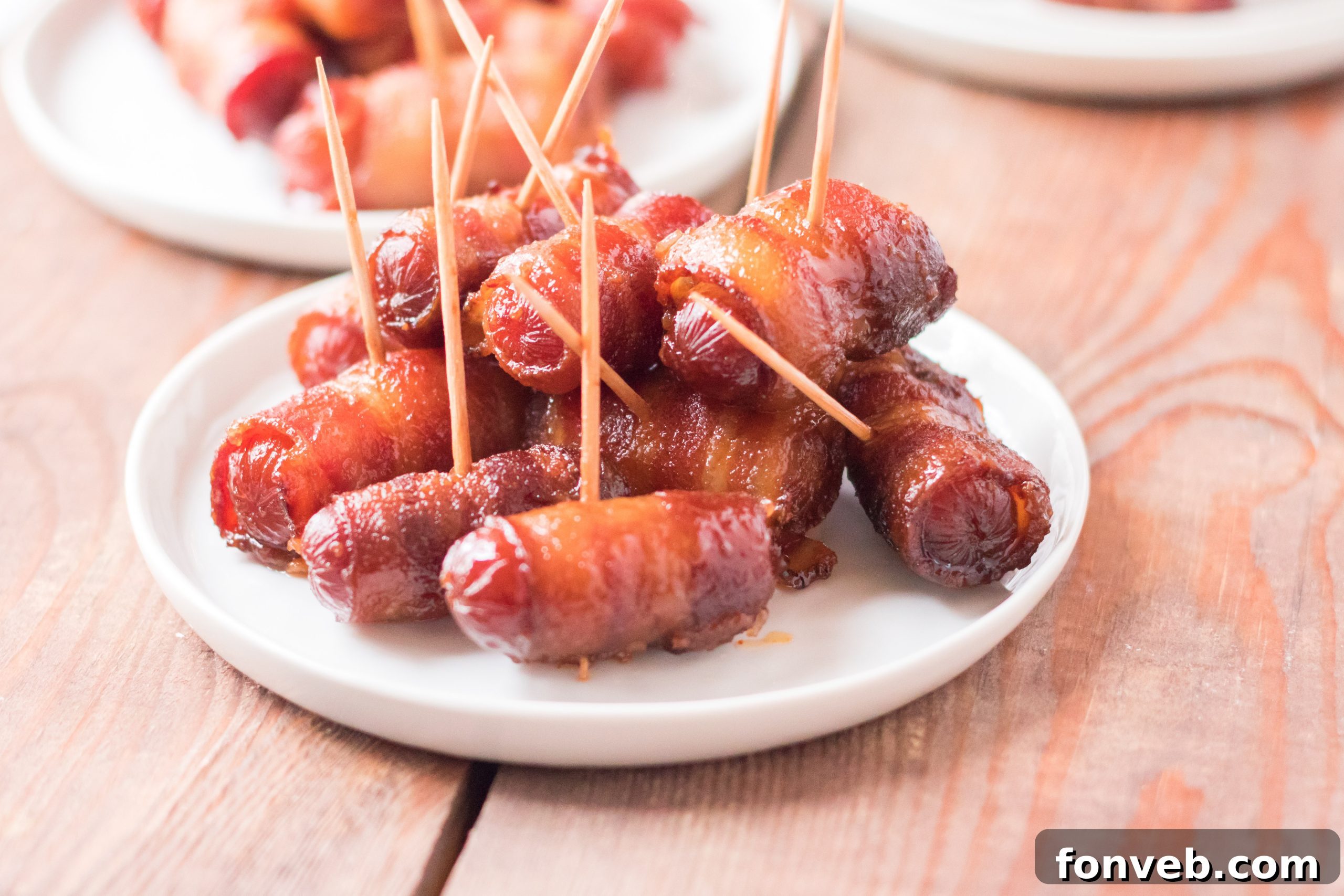 A close-up shot of a single Slow Cooker Bacon Wrapped Smokie, highlighting the thick-cut bacon and brown sugar glaze.