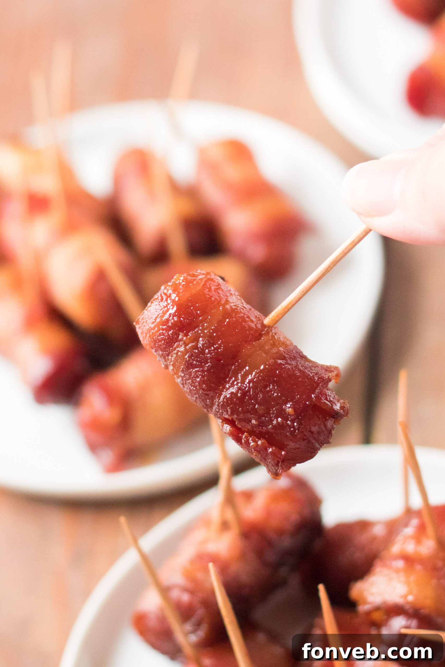 A close-up of a serving of Slow Cooker Bacon Wrapped Smokies, ready to be picked up.