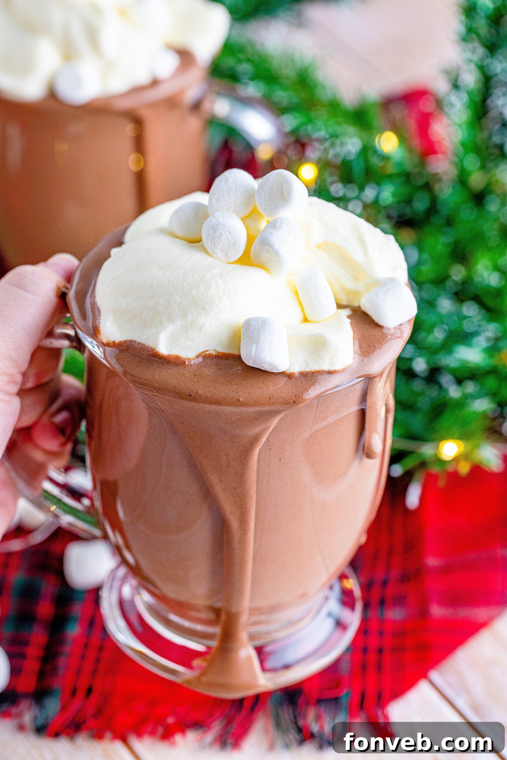A mug of incredibly creamy and rich slow cooker hot chocolate, garnished with whipped cream and chocolate shavings, set against a cozy background.