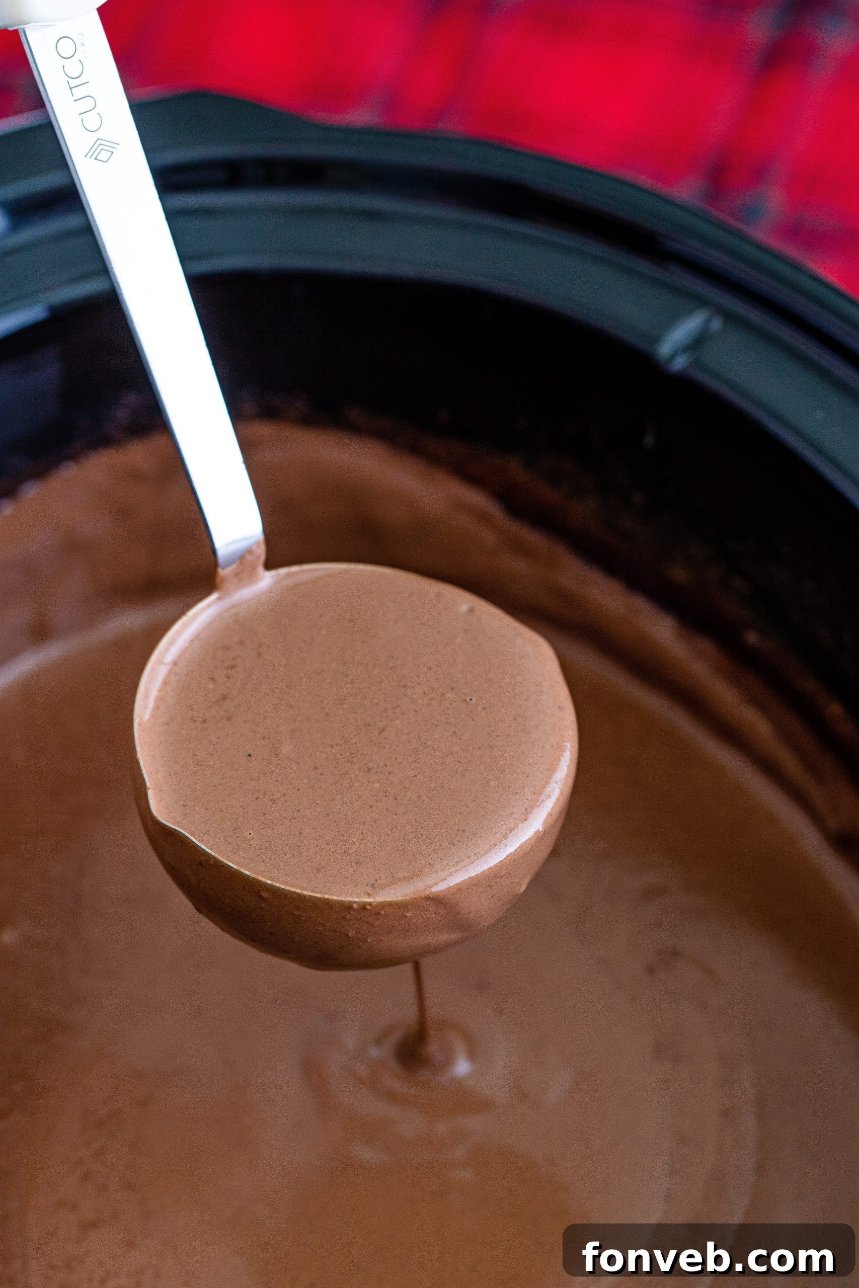 An inviting display of alcoholic additions such as Baileys Irish Cream and RumChata, arranged around a slow cooker filled with hot chocolate for a festive adult beverage station.