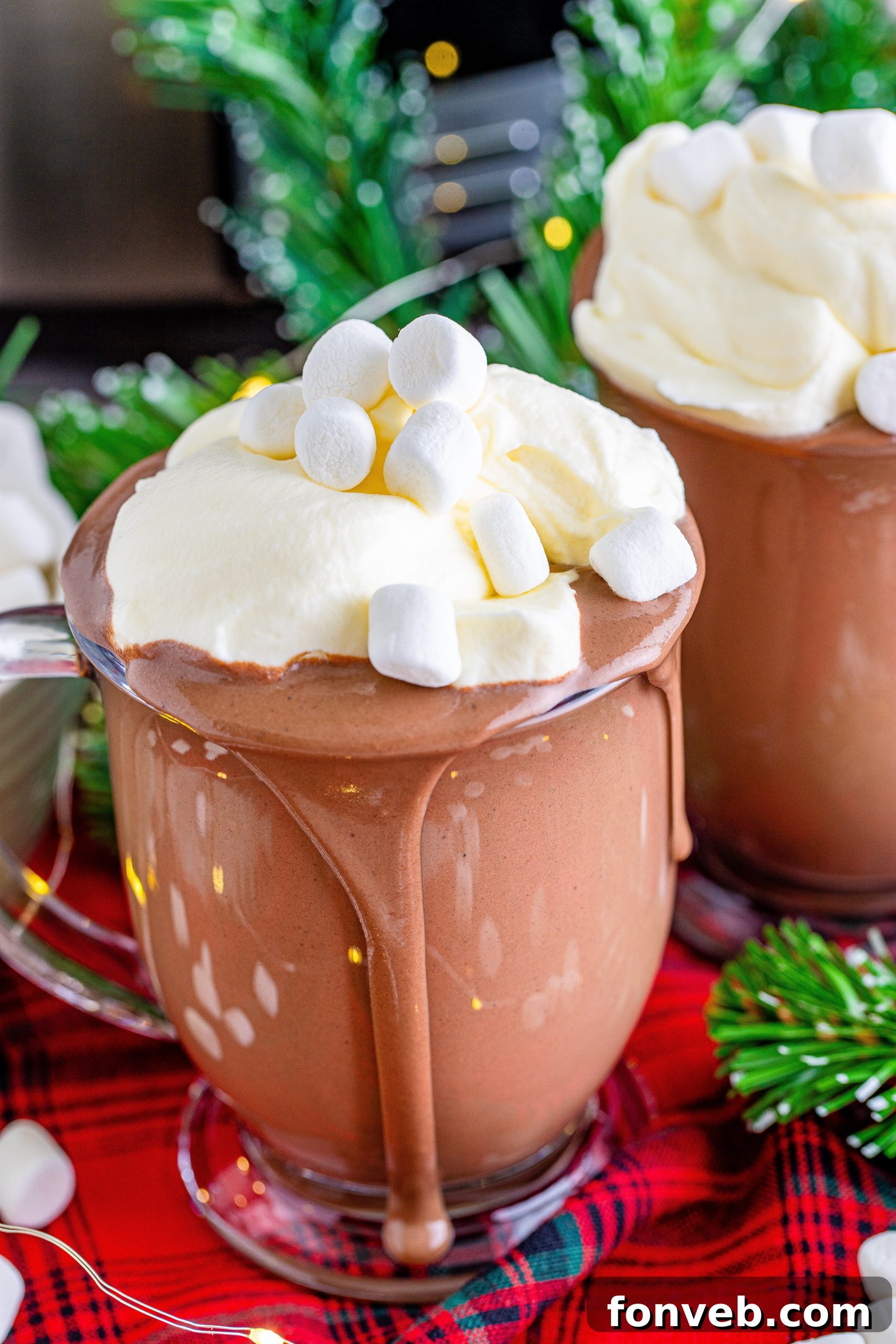 A beautifully arranged holiday hot chocolate bar with a slow cooker of hot chocolate, an assortment of toppings, and festive decorations, perfect for a party.