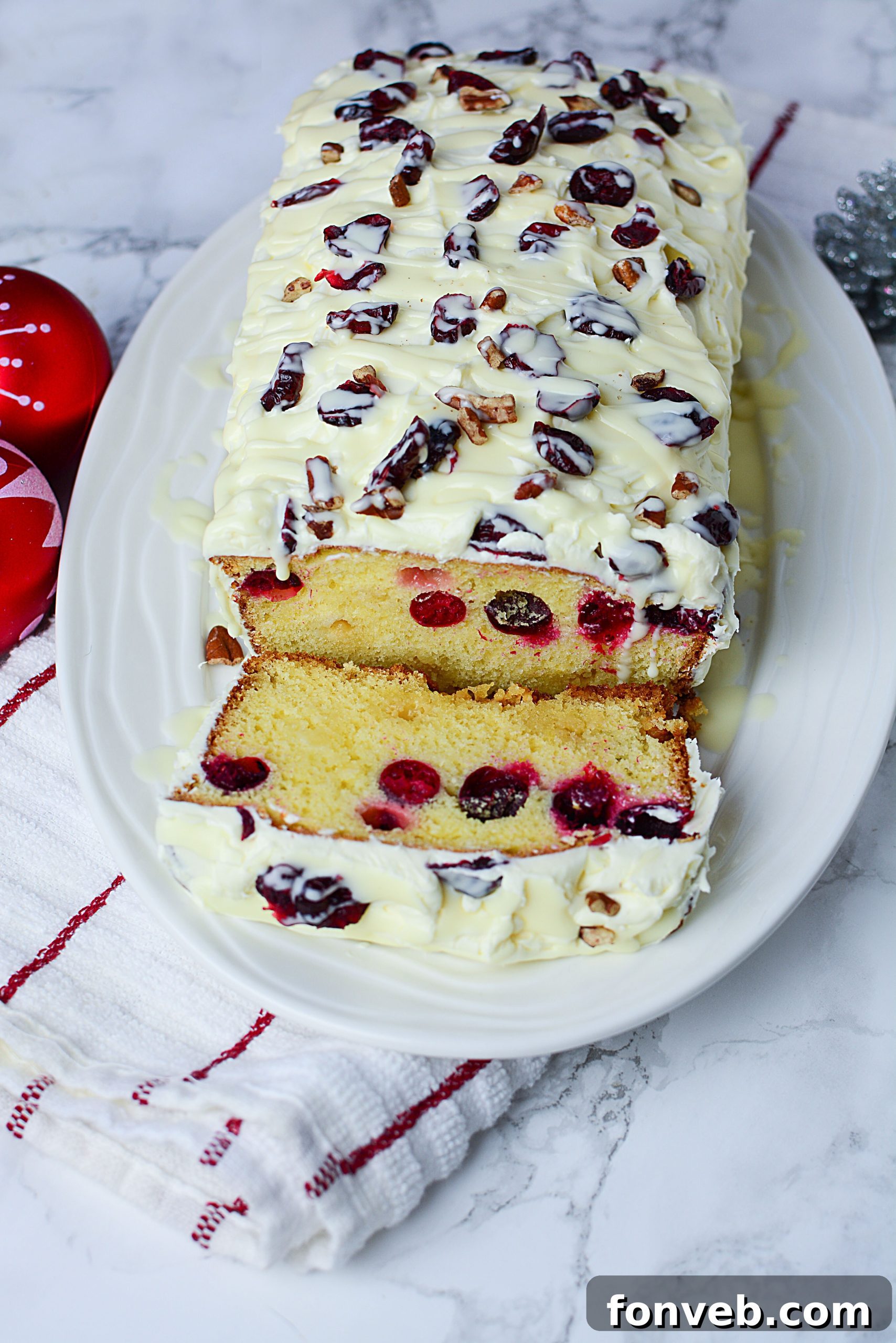 Crimson Cranberry Holiday Cake 5 Hand holding a slice of delicious Cranberry Pound Cake with decadent cream cheese frosting.