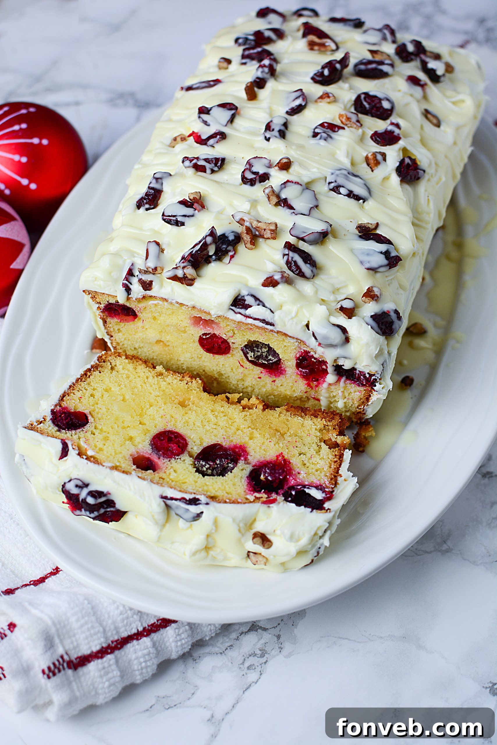 Crimson Cranberry Holiday Cake 7 Overhead shot of a Cranberry Pound Cake, garnished with cranberries, white chocolate drizzle, and chopped nuts.