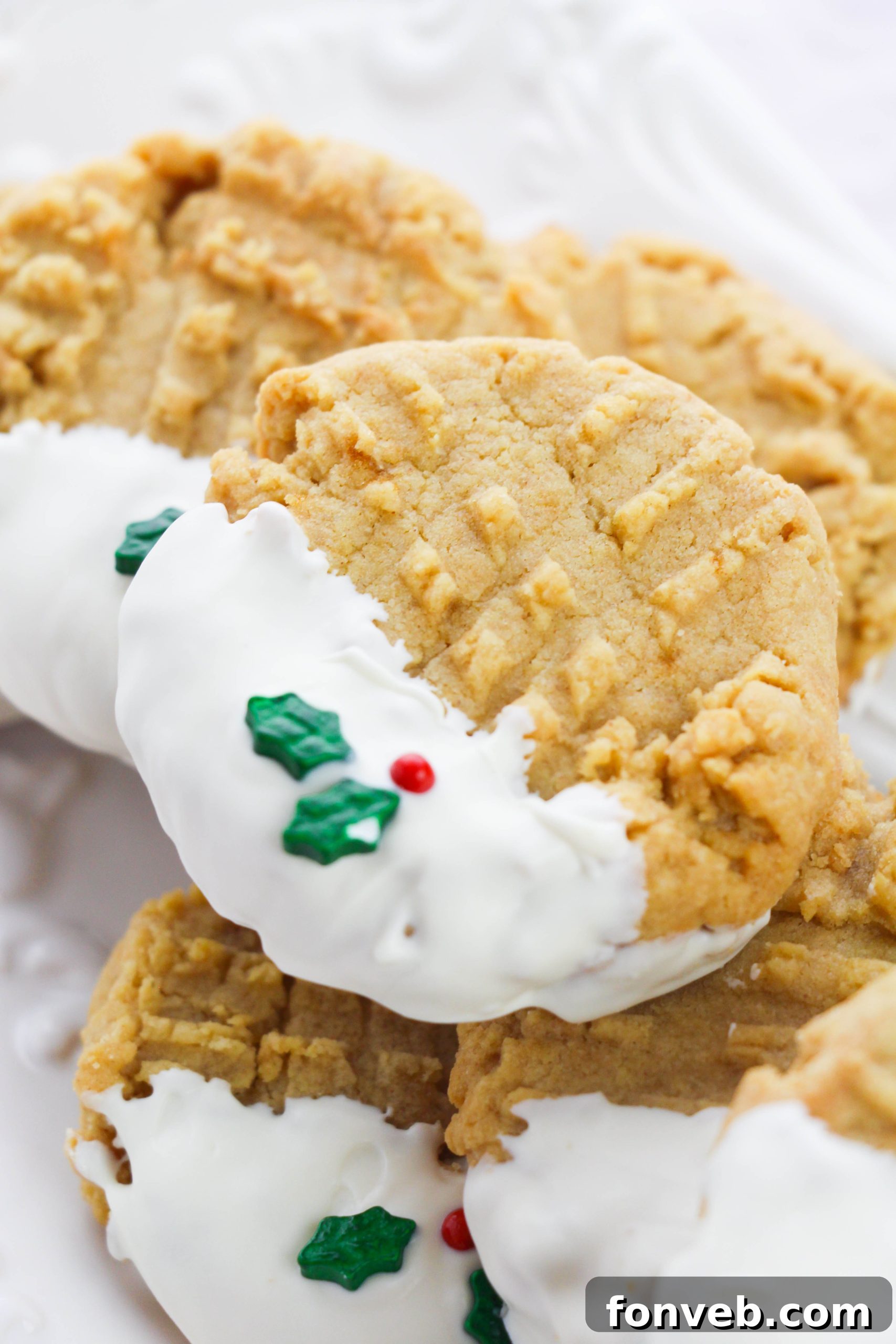 A hand reaching for a white chocolate dipped peanut butter cookie from a platter, ready to enjoy