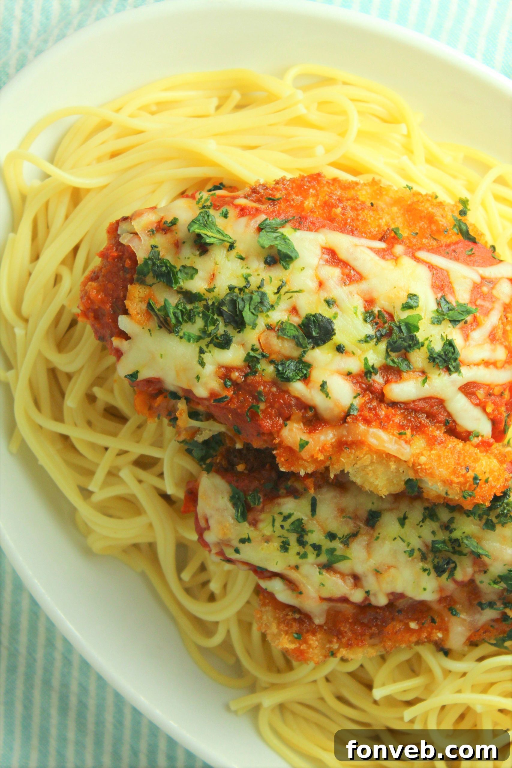 Chicken Parmesan baking in a dish, cheese melting and bubbling.