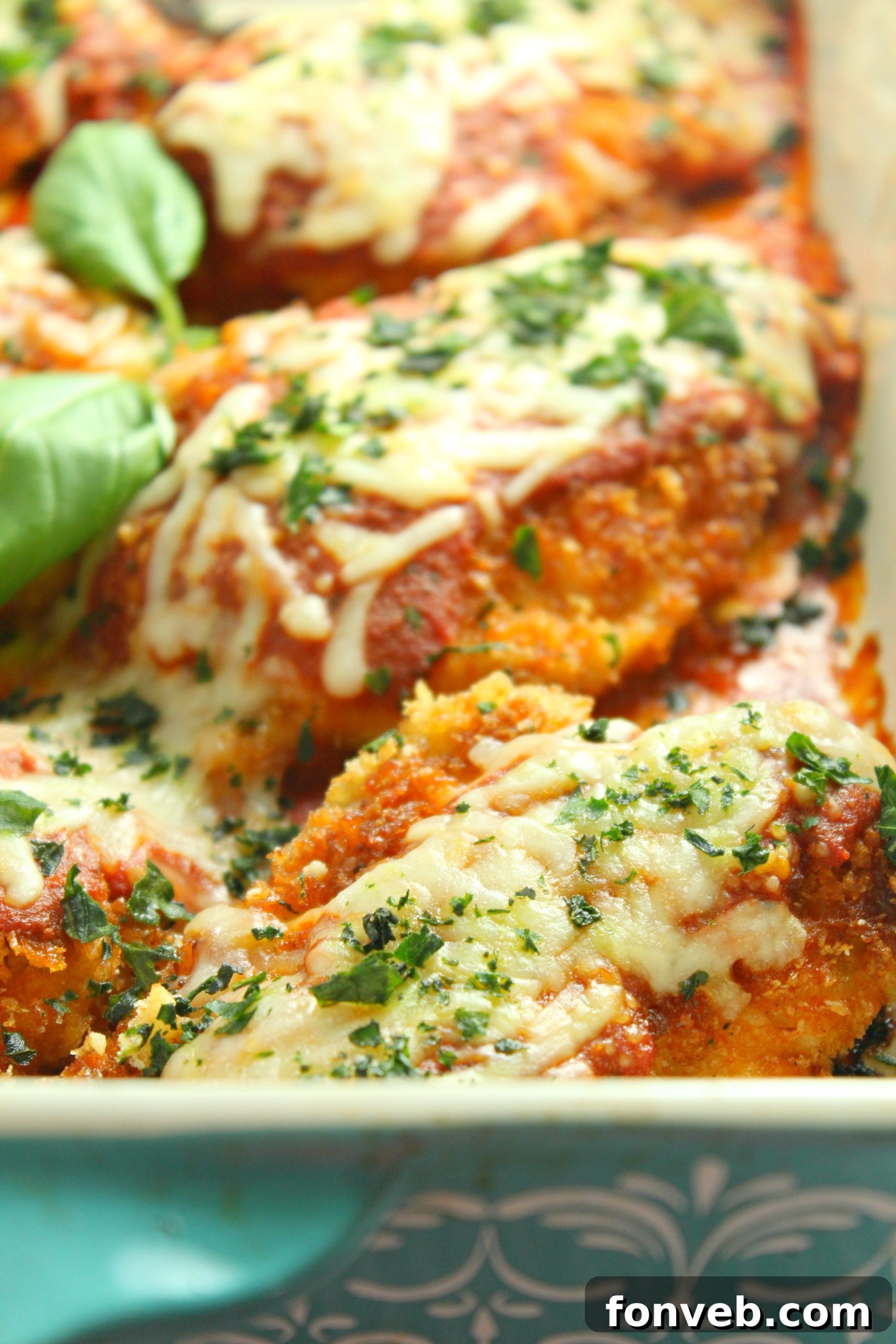 Chicken Parmesan garnished with fresh basil leaves.