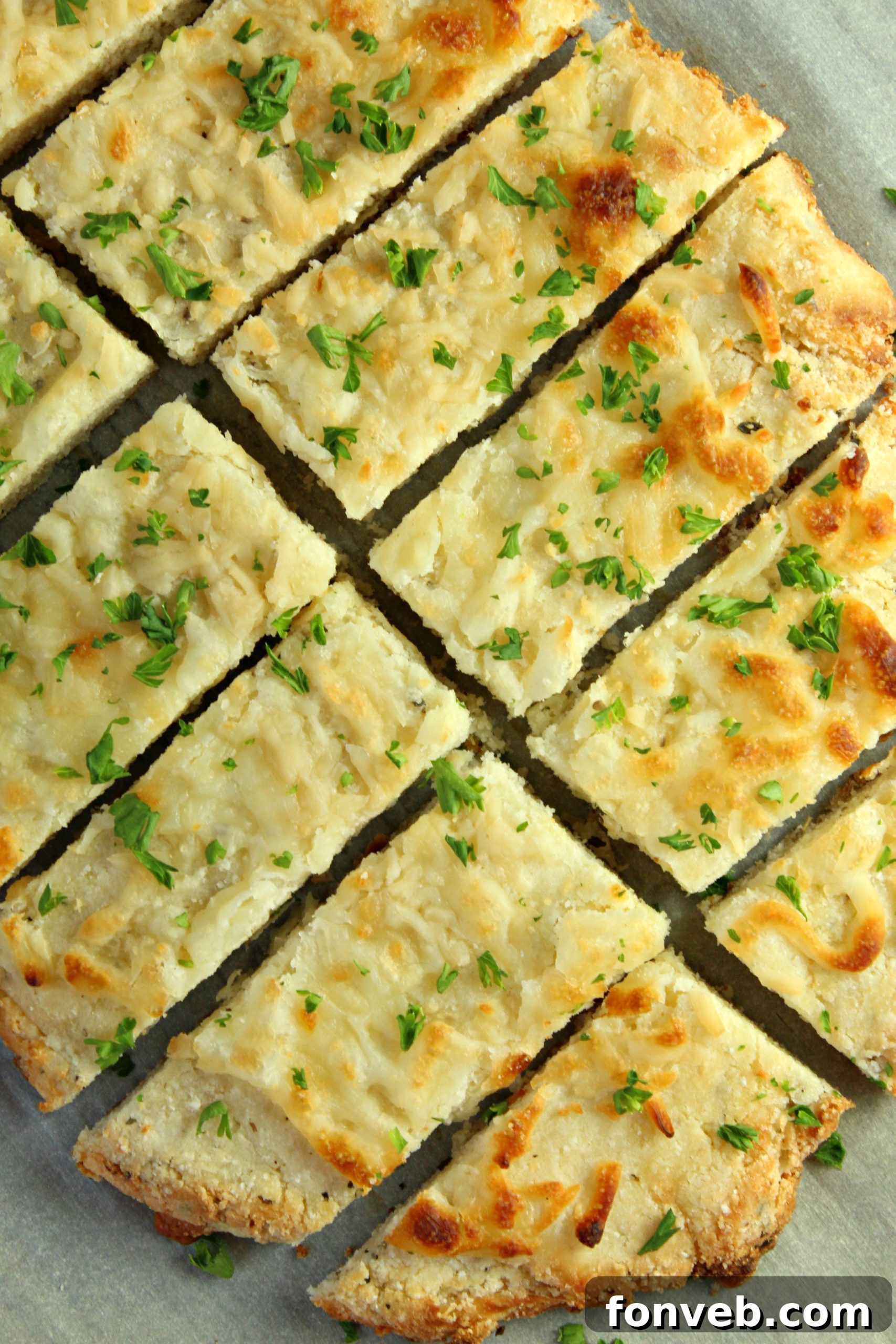 Another perspective of the cheesy keto breadsticks on a wooden surface, highlighting their texture.