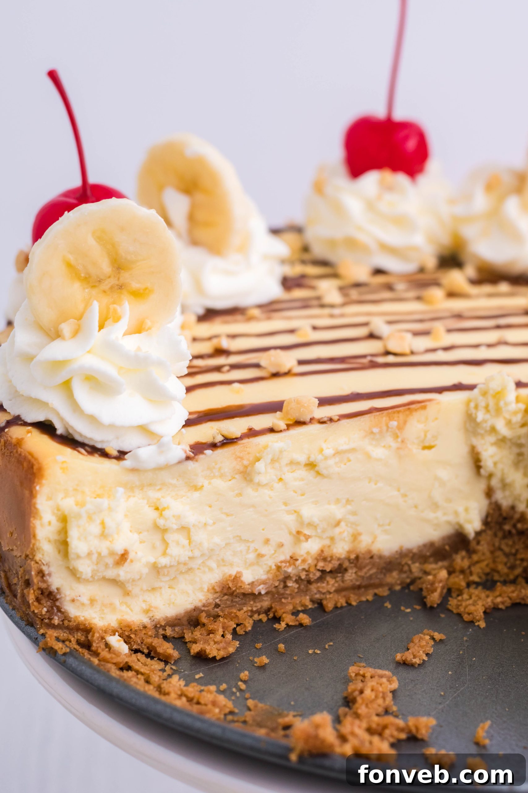 A beautifully sliced Banana Split Cheesecake showing its creamy filling and graham cracker crust, adorned with fresh toppings.