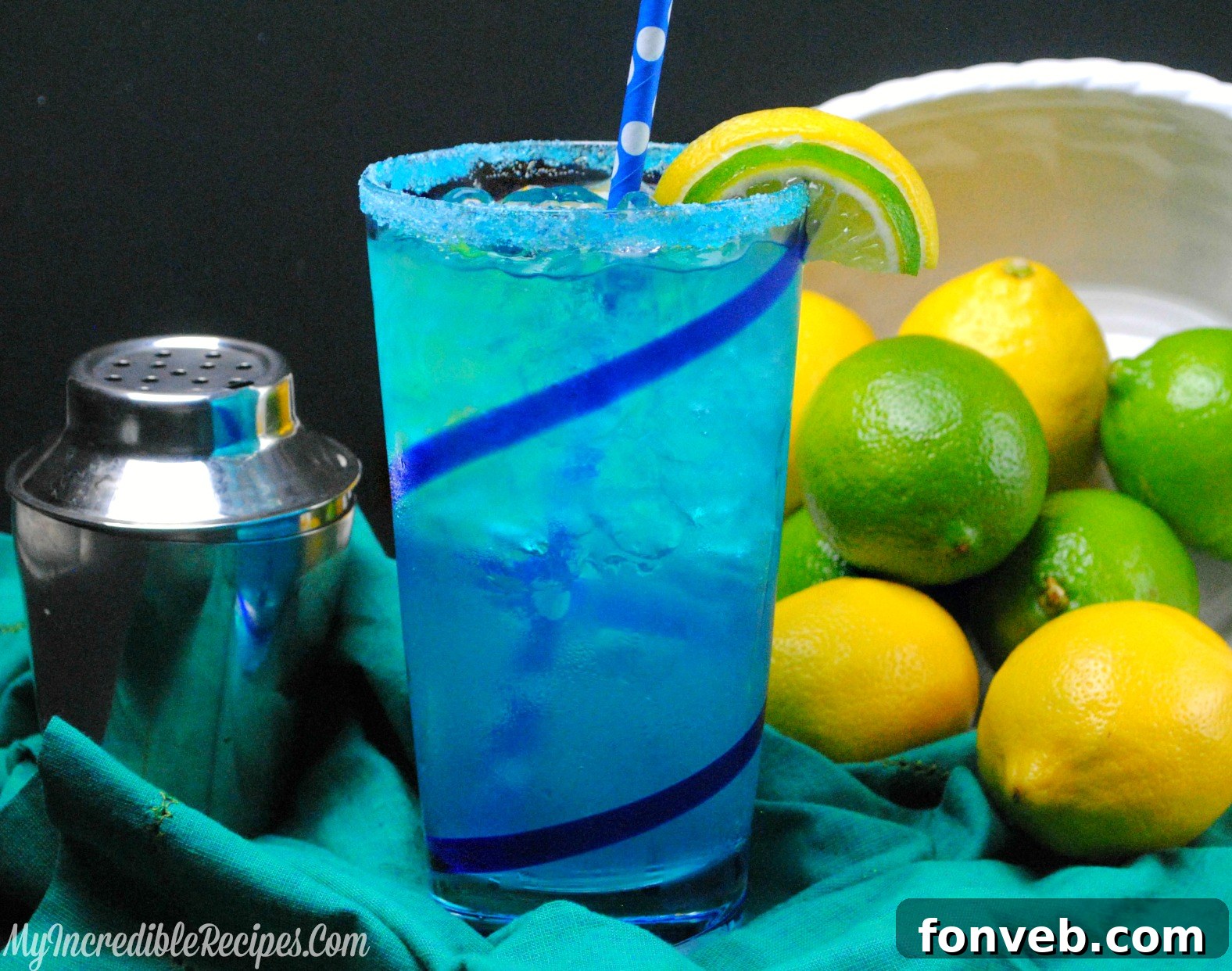 Two elegantly presented glasses of Electric Lemonade, garnished with fresh lime and lemon slices, showcasing its vibrant and inviting blue color on a light surface