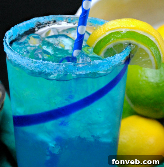 A flat lay photograph featuring the key ingredients for Electric Lemonade: a bottle of citron vodka, blue curacao liqueur, fresh lemons and limes, and ice cubes, all arranged on a rustic wooden background