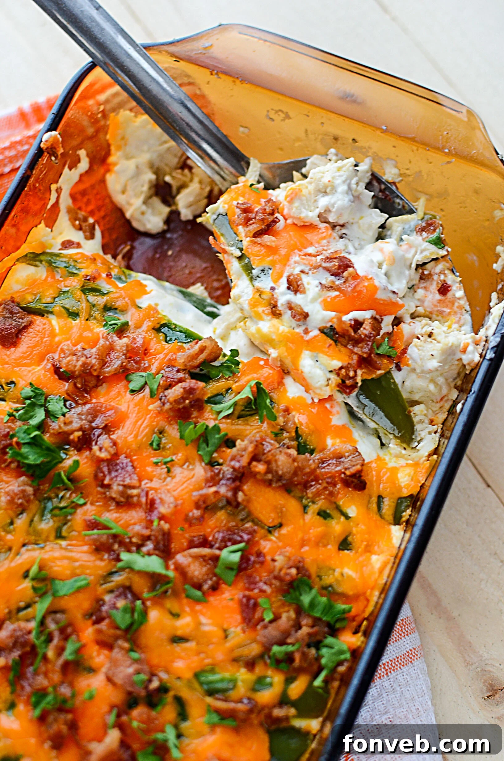 A top-down view of a creamy Jalapeño Popper Chicken Casserole, topped with crispy bacon and melted cheese.