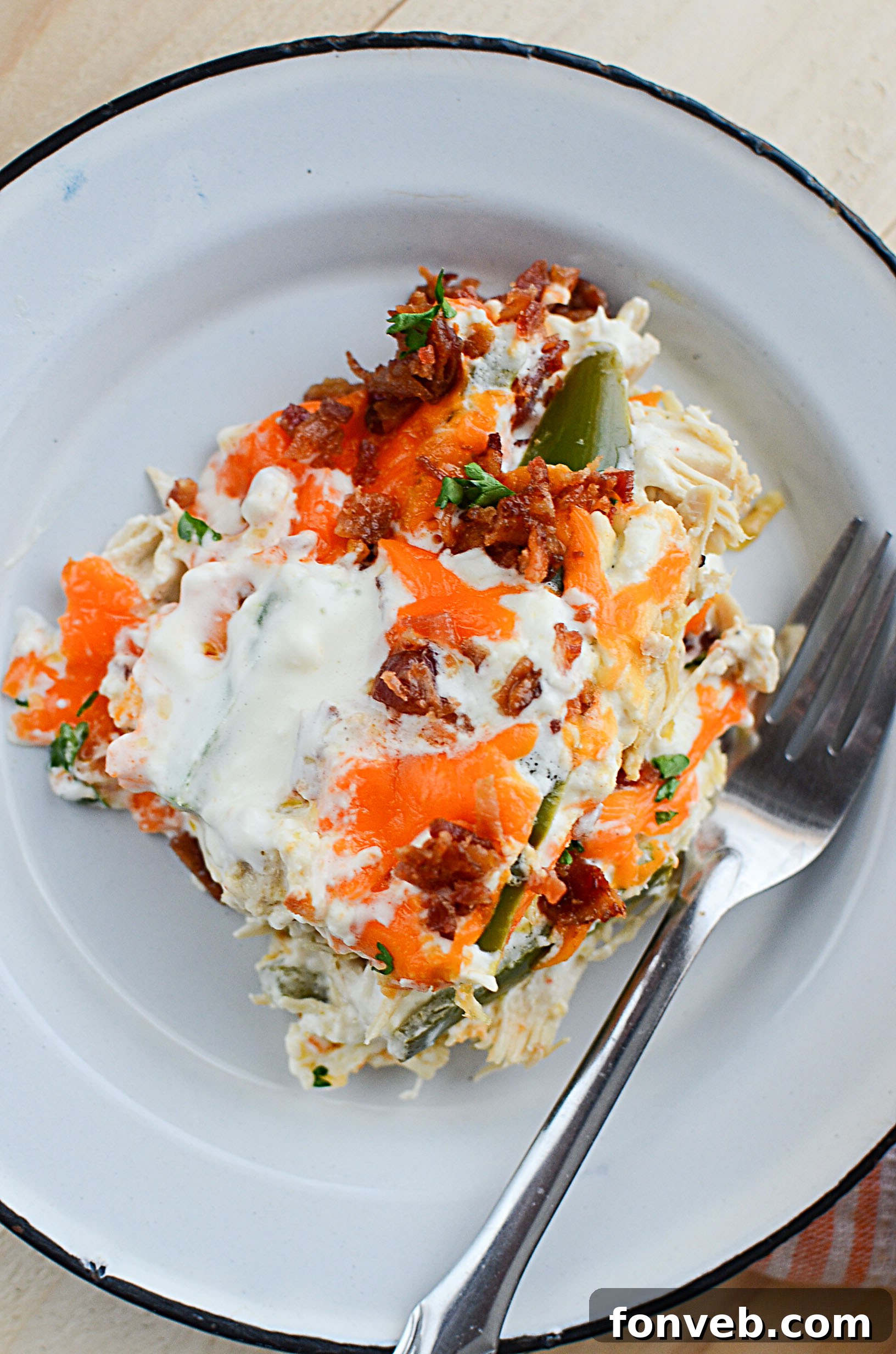 A finished serving of Jalapeño Popper Chicken Casserole on a plate, garnished with fresh herbs.