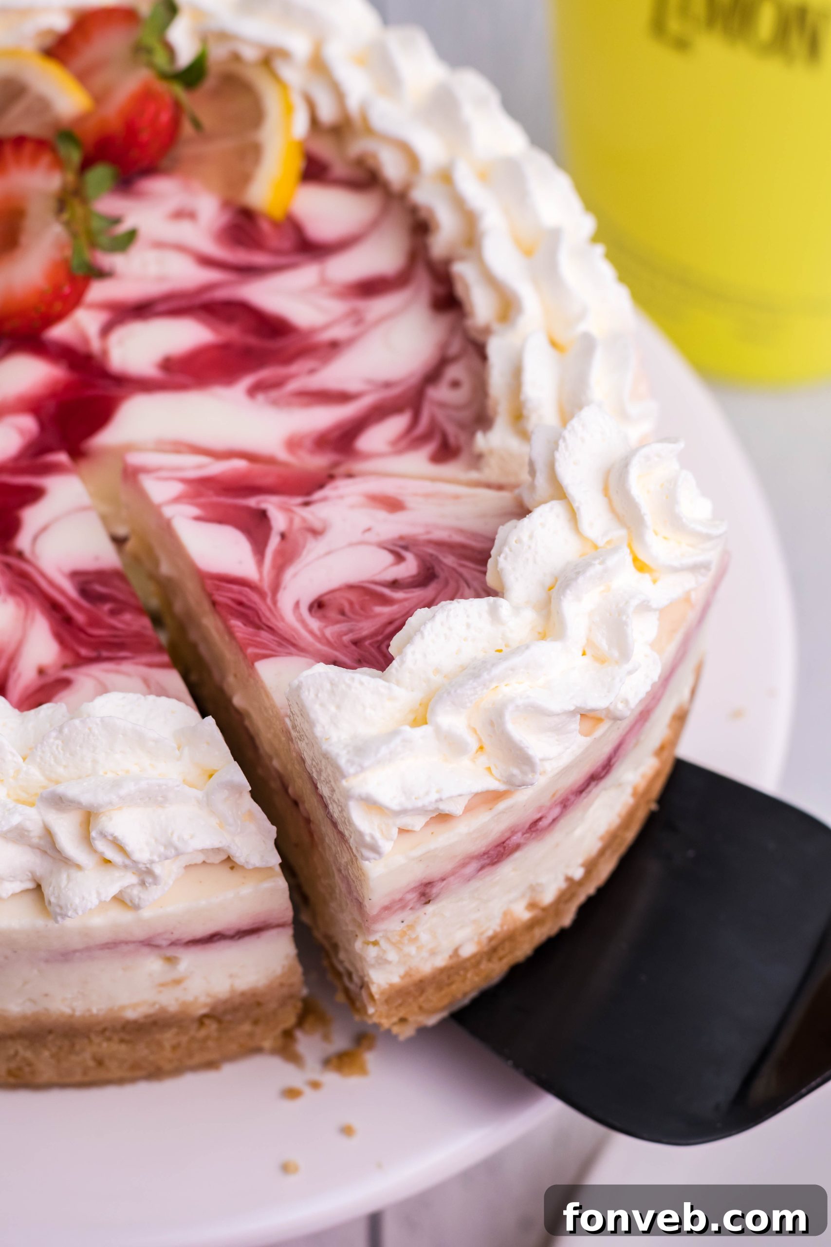 Another view of a delicious slice of Strawberry Lemon RumChata cheesecake with fresh garnishes.