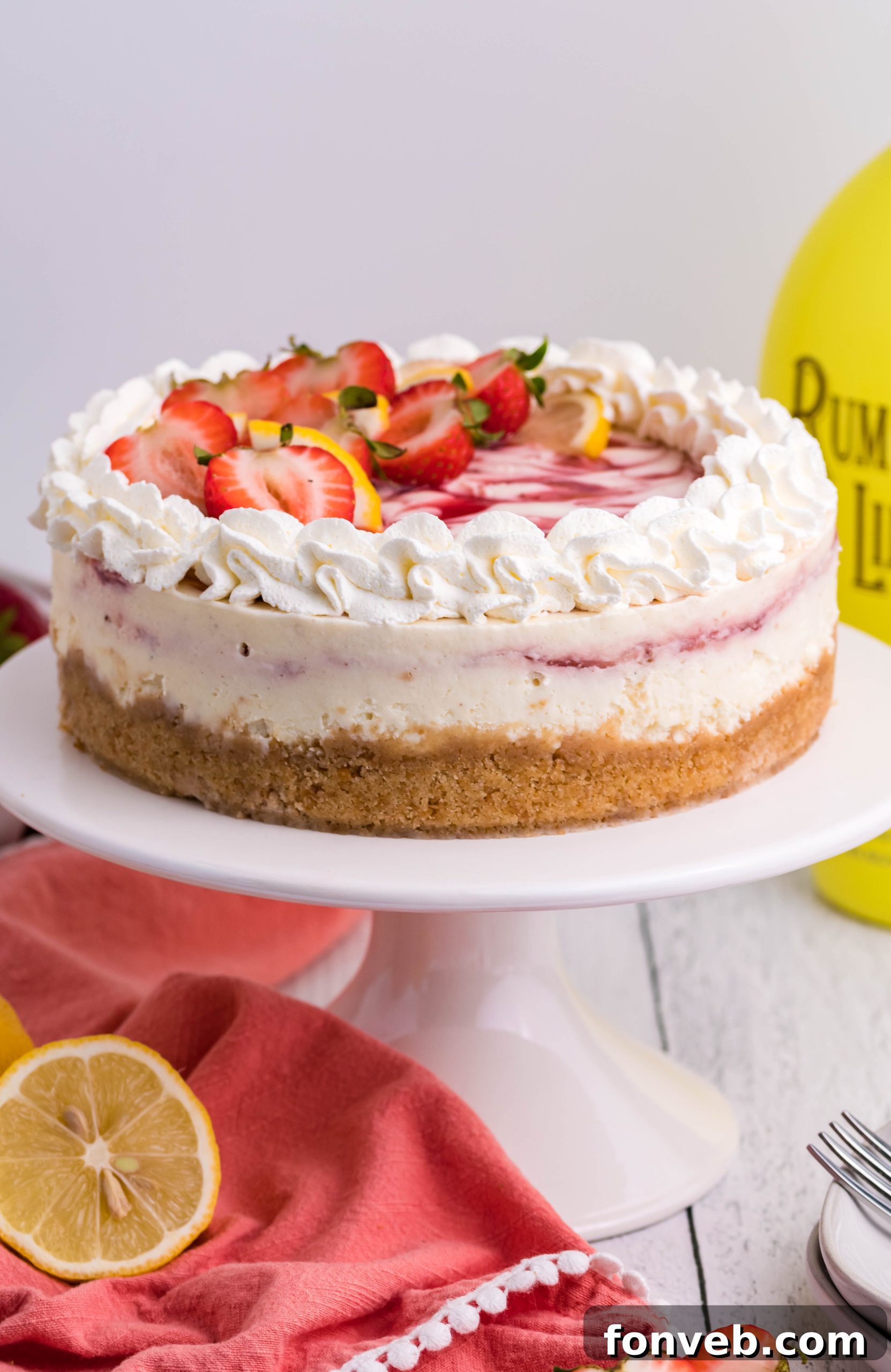 Top-down view of an entire Strawberry Lemon RumChata Cheesecake, garnished with fresh fruit and whipped topping.