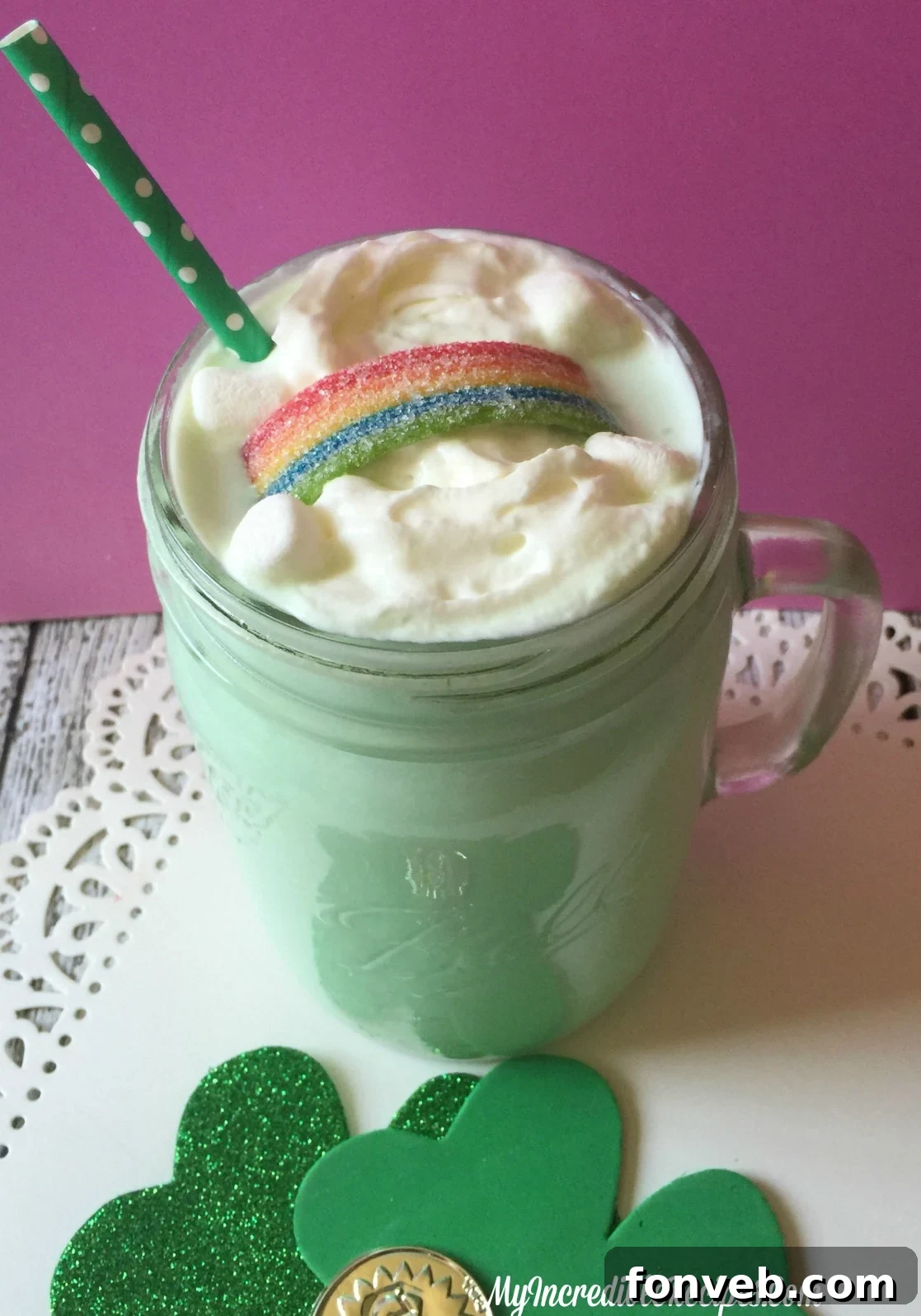 A festive glass of Shamrock Cocoa, garnished with whipped cream, mini marshmallows, and a colorful rainbow candy strip
