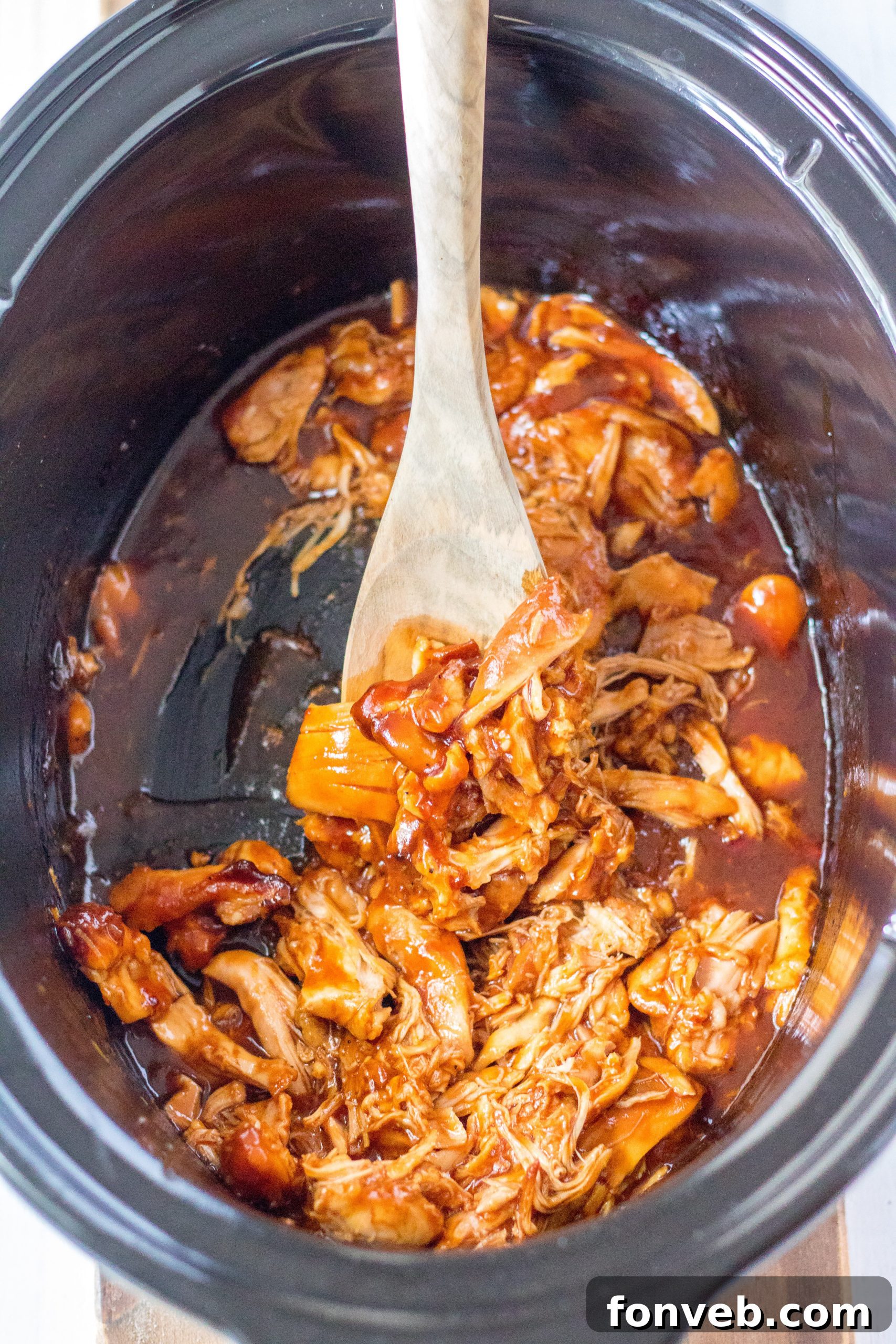 Slow Cooker Root Beer Chicken with extra sauce and a spoon