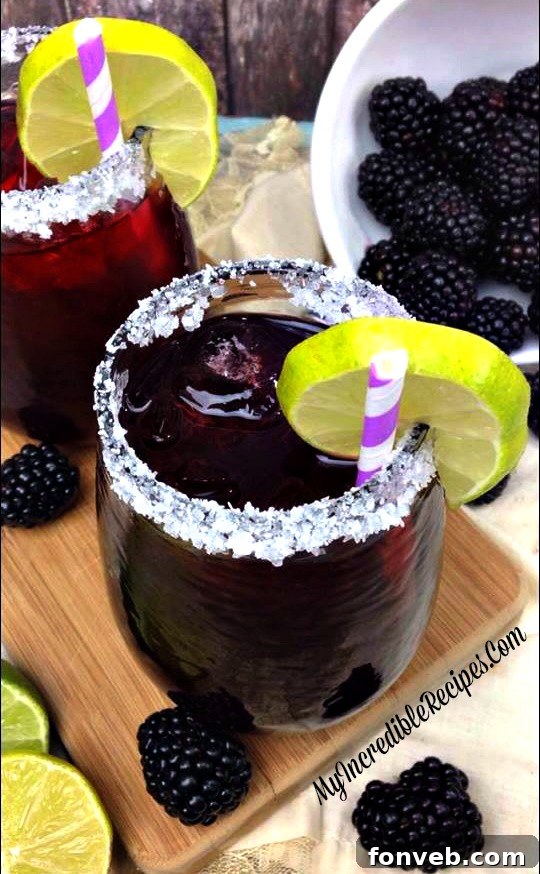Two Blackberry Margaritas on a table with a dimly lit background