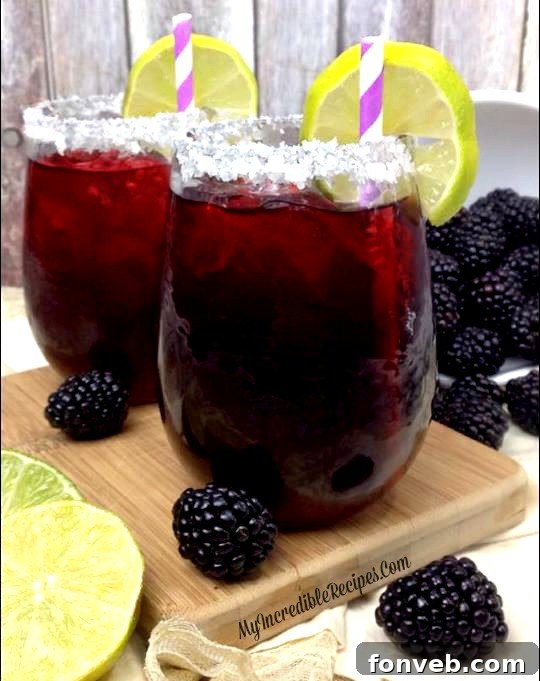 Close-up of a blackberry margarita being garnished with a lime wheel