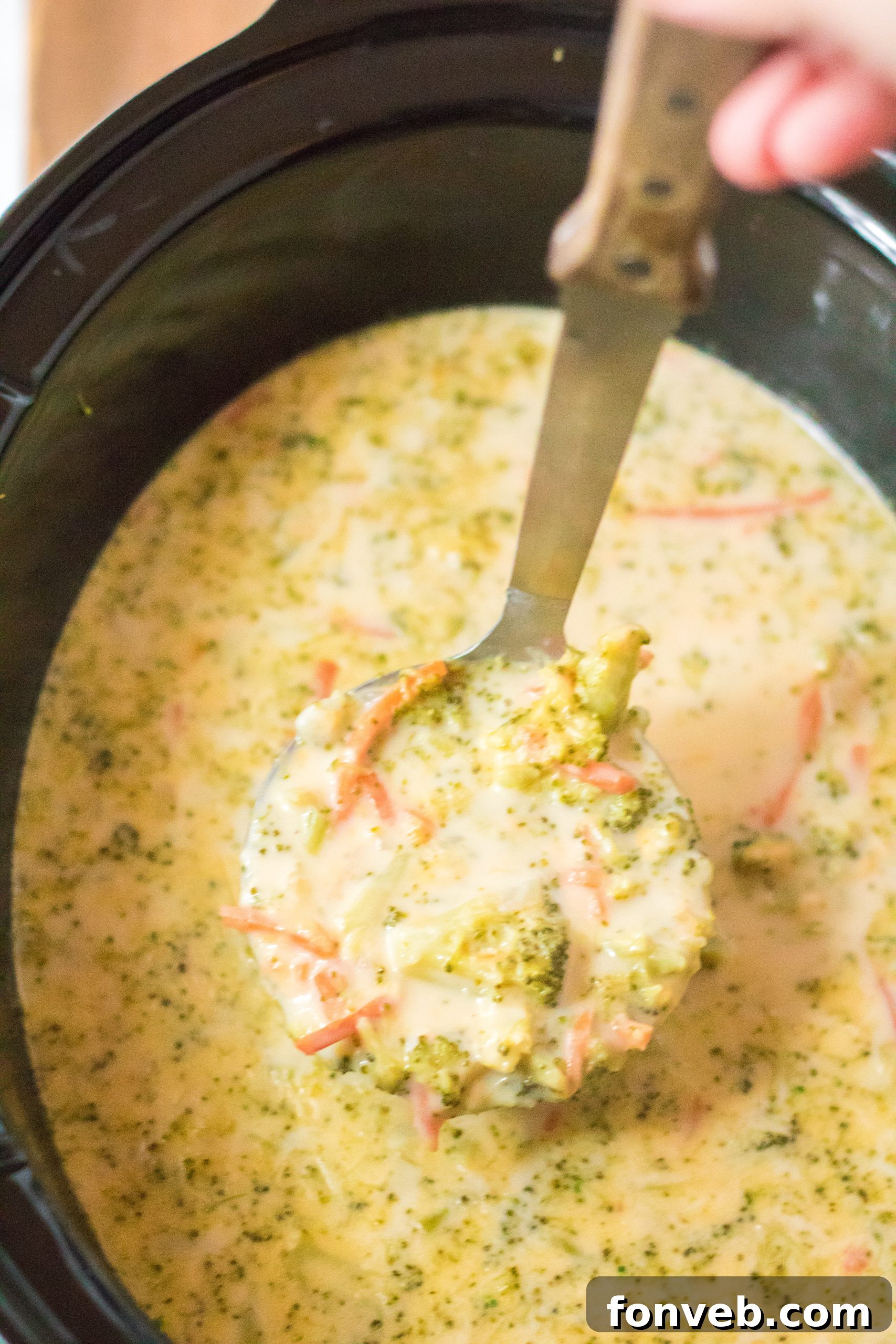 A bowl of slow cooker broccoli cheddar soup ready to eat, served with bread