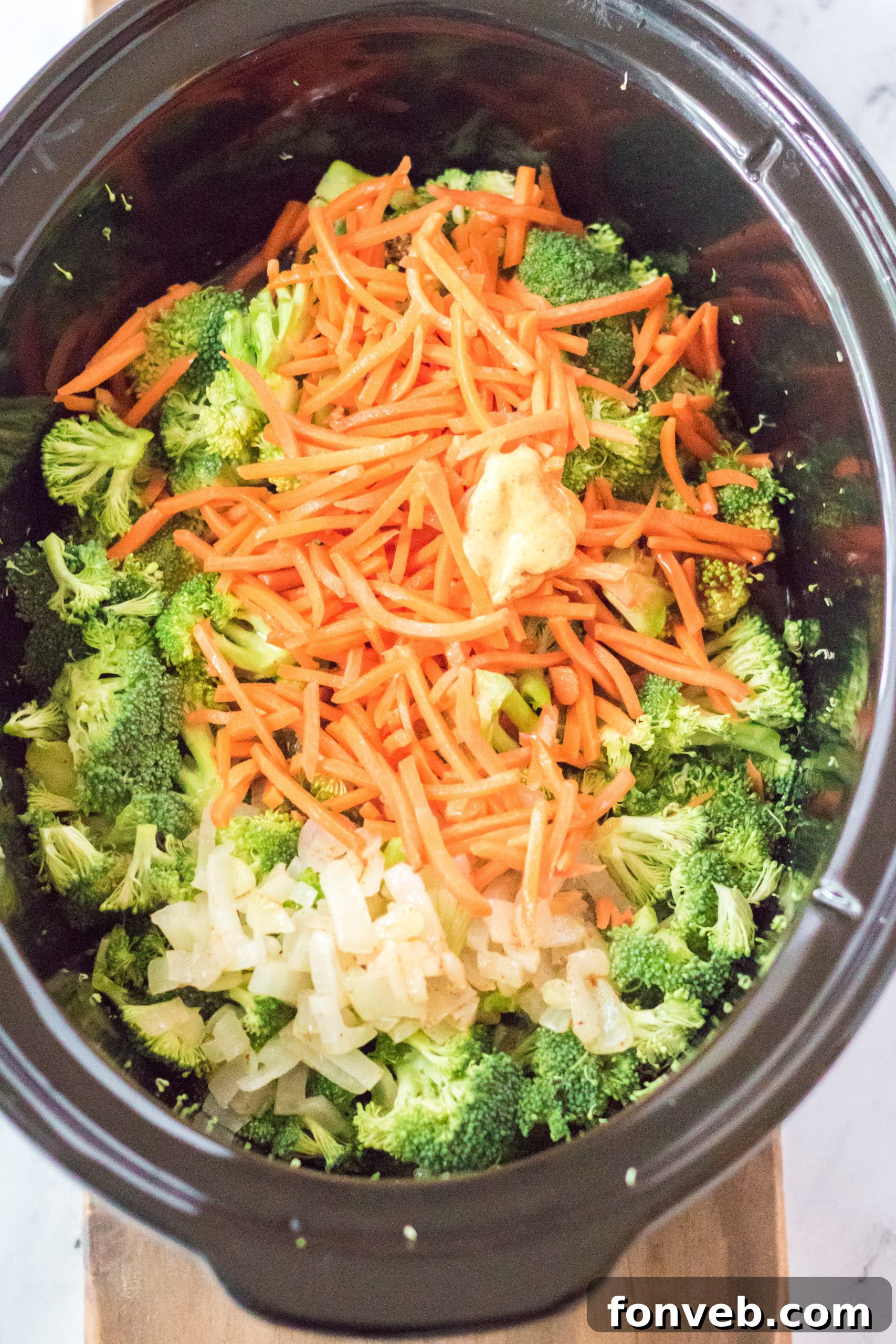 Broccoli cheddar soup being poured from a ladle into a white serving bowl