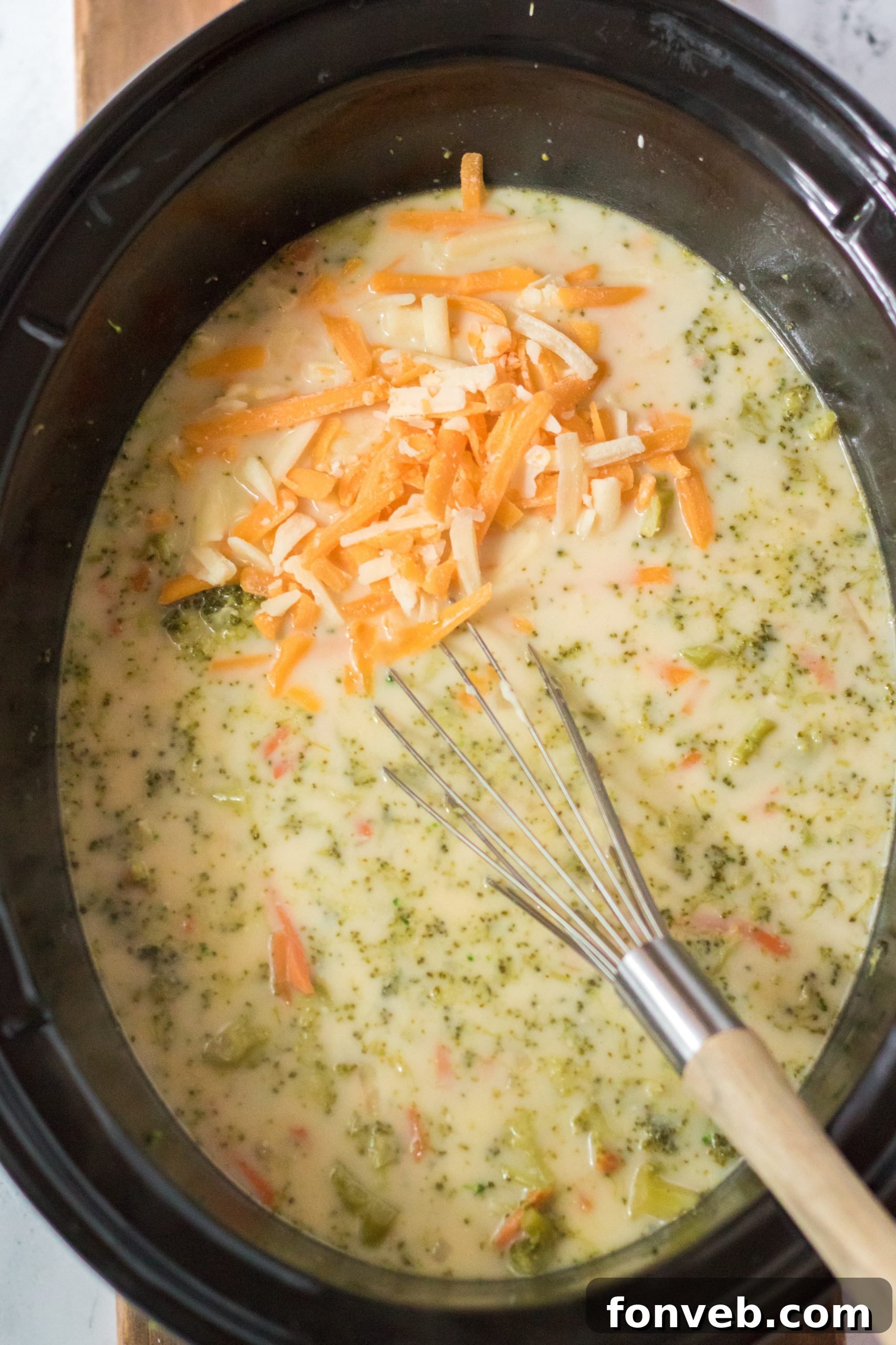 Various fresh ingredients like broccoli, carrots, onion, and cheese arranged on a cutting board