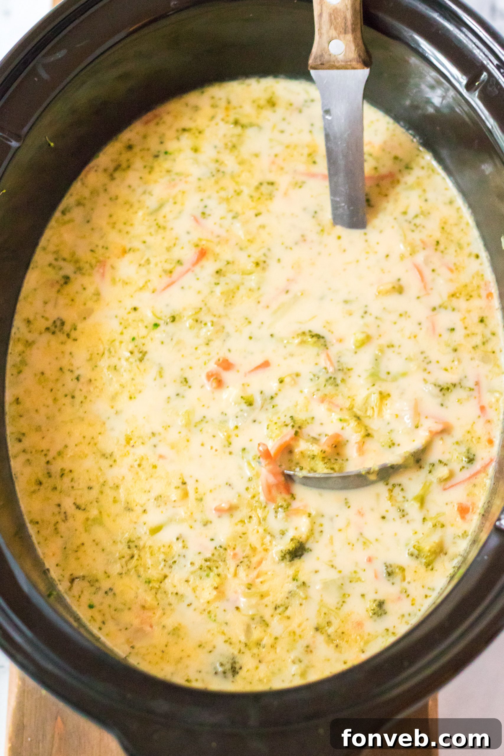 Broccoli cheddar soup gently simmering in a slow cooker, steam rising