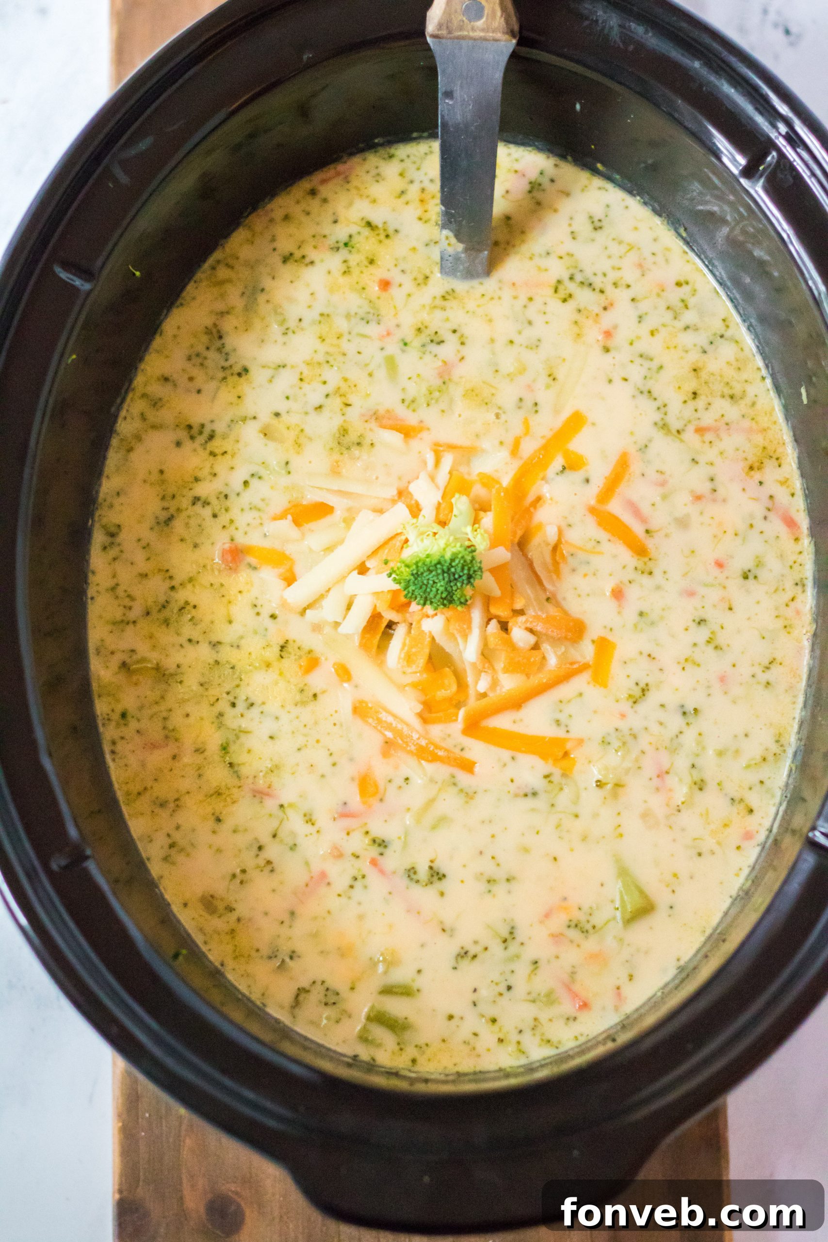 A beautifully presented bowl of creamy broccoli cheddar soup with fresh bread on the side
