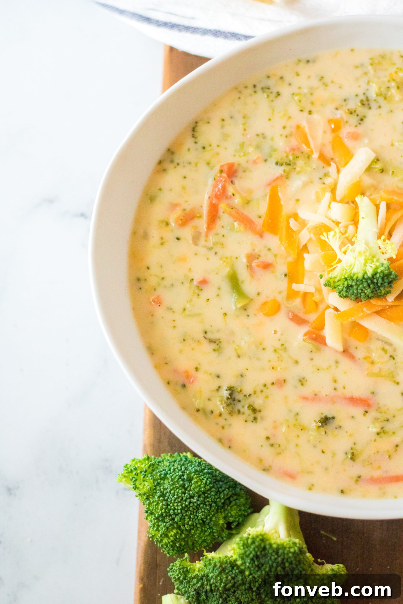 A rustic bowl of homemade broccoli cheese soup, garnished with fresh herbs and a spoon