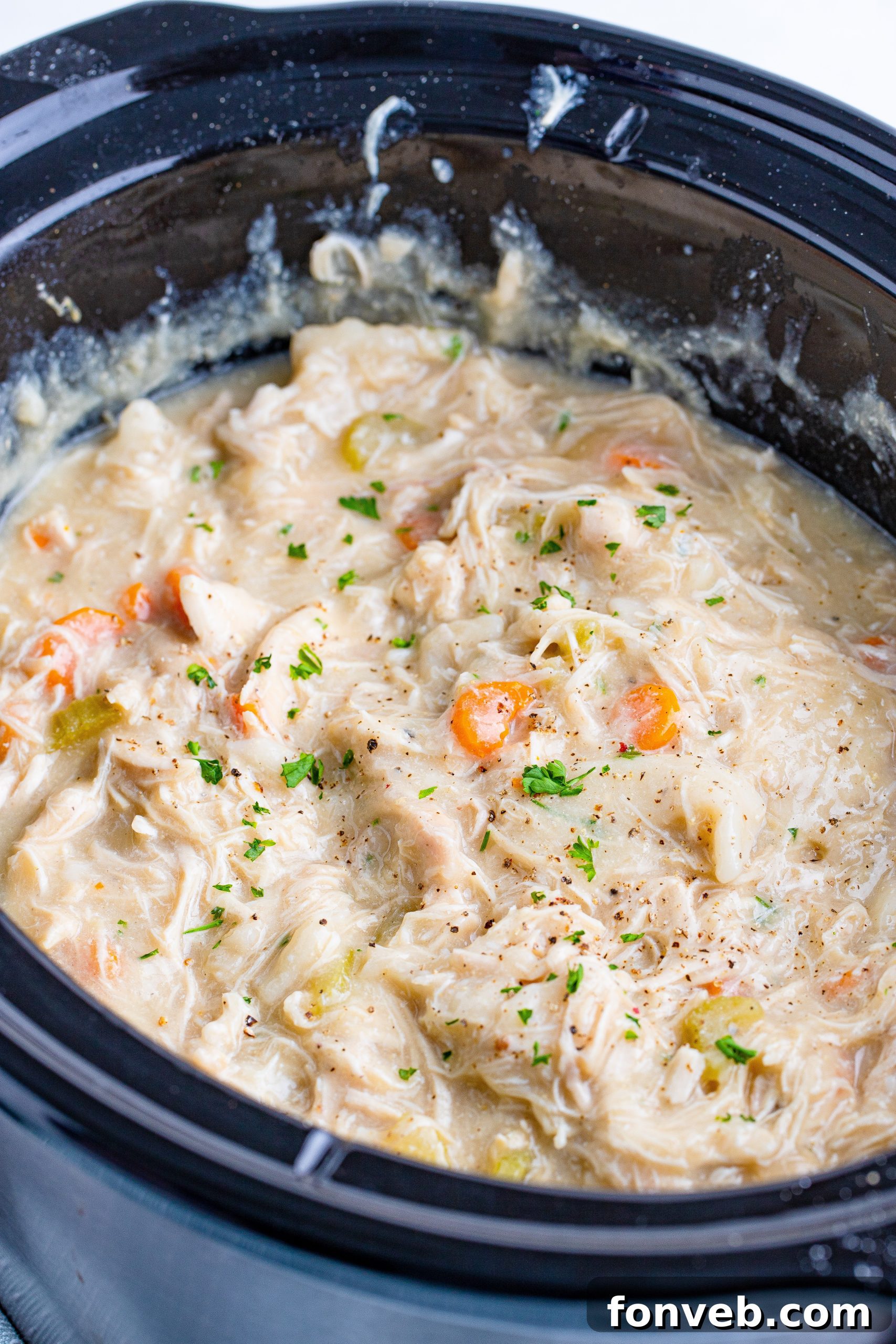 Fresh ingredients laid out for a slow cooker chicken and dumplings recipe, including cubed chicken, carrots, and celery