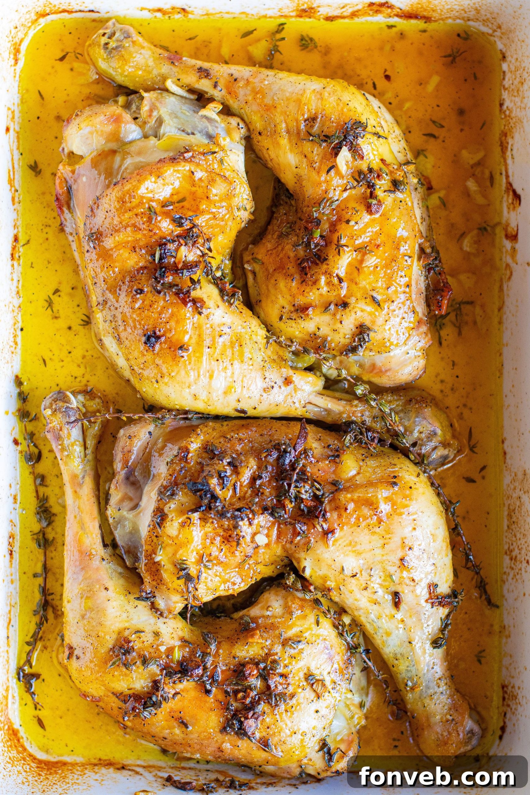 Golden brown, crispy baked chicken thighs resting in a baking dish, surrounded by pan juices.