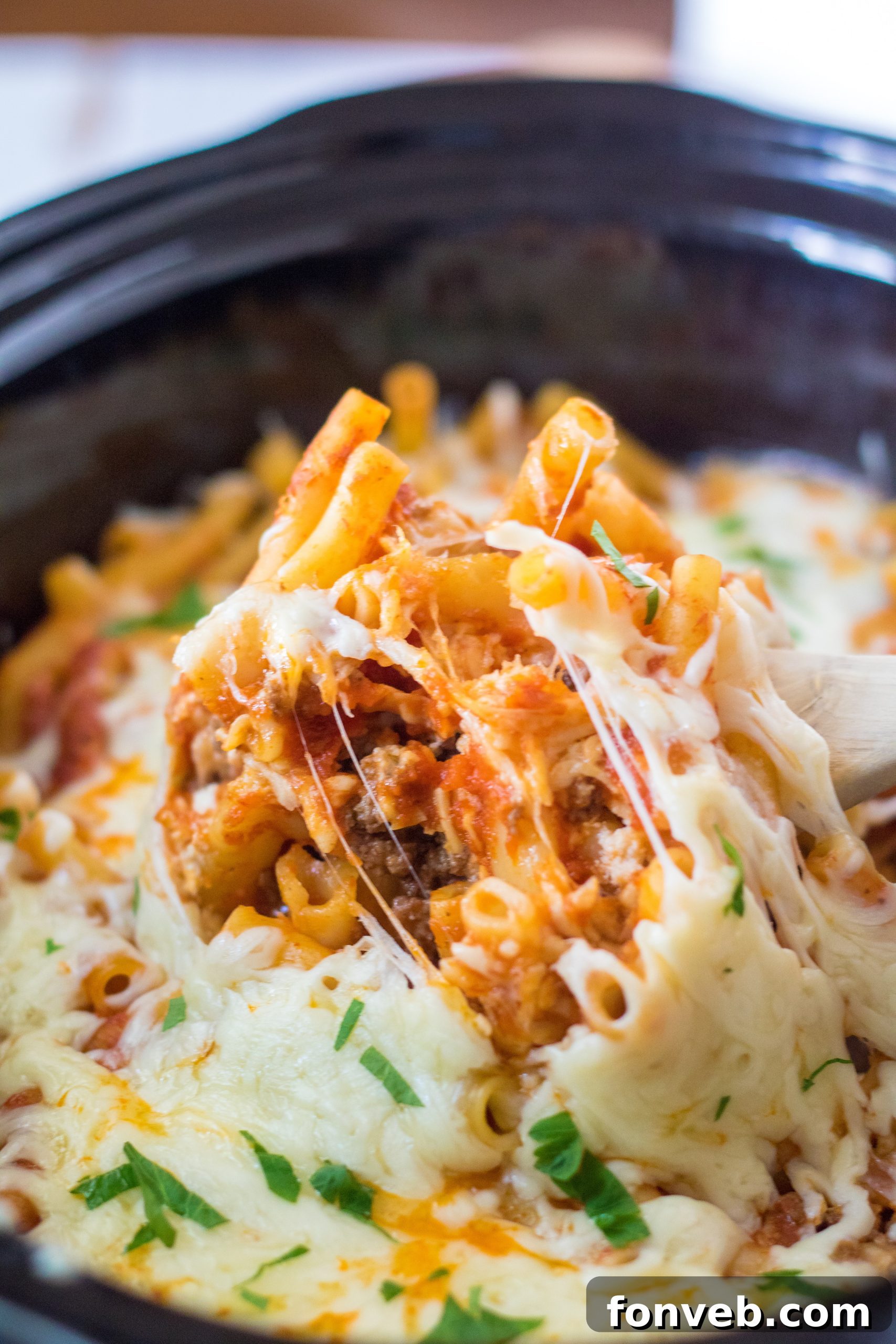 Slow cooker filled with delicious, bubbling cheesy baked ziti.