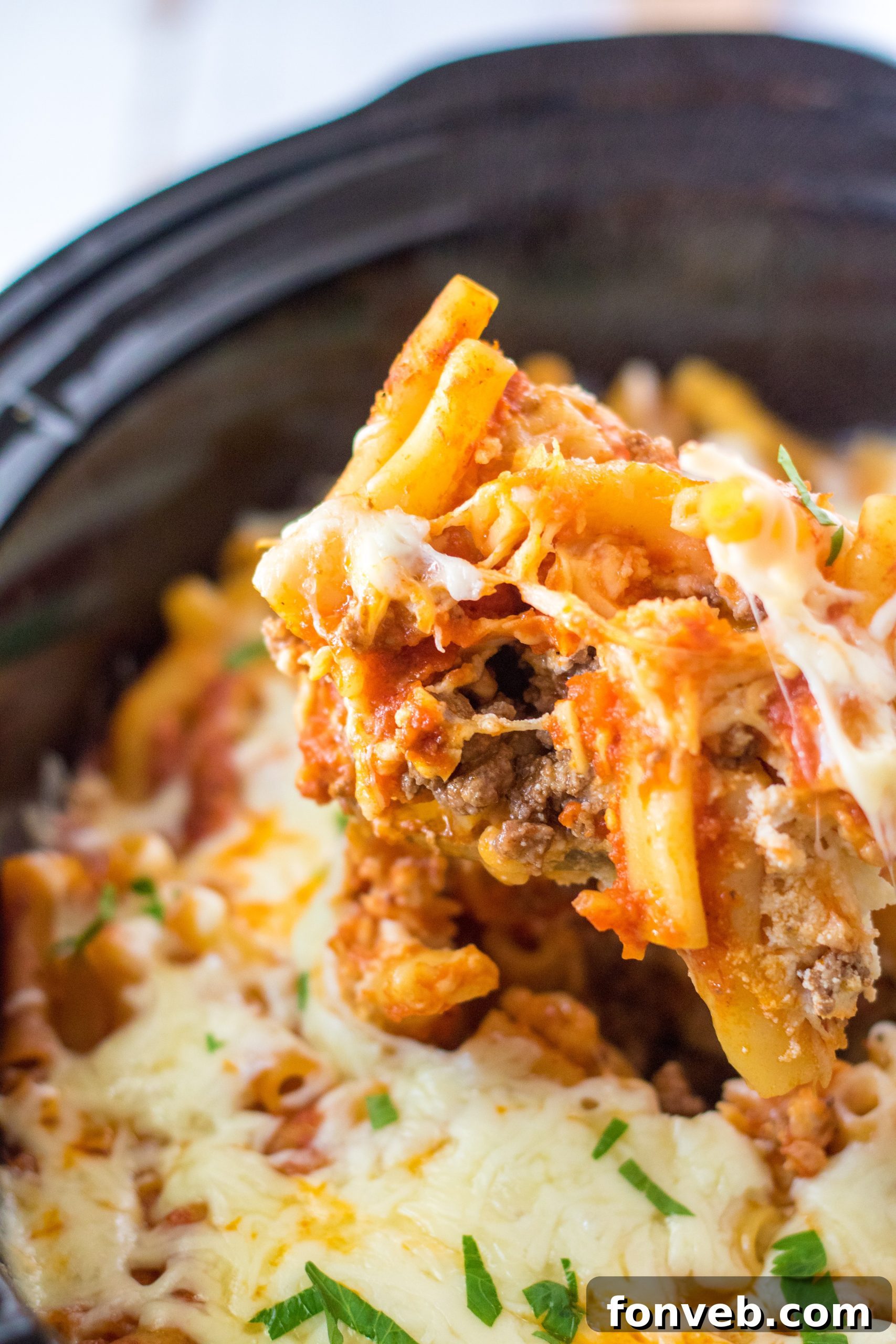 A serving of Slow Cooker Cheesy Baked Ziti on a plate with fresh basil garnish.