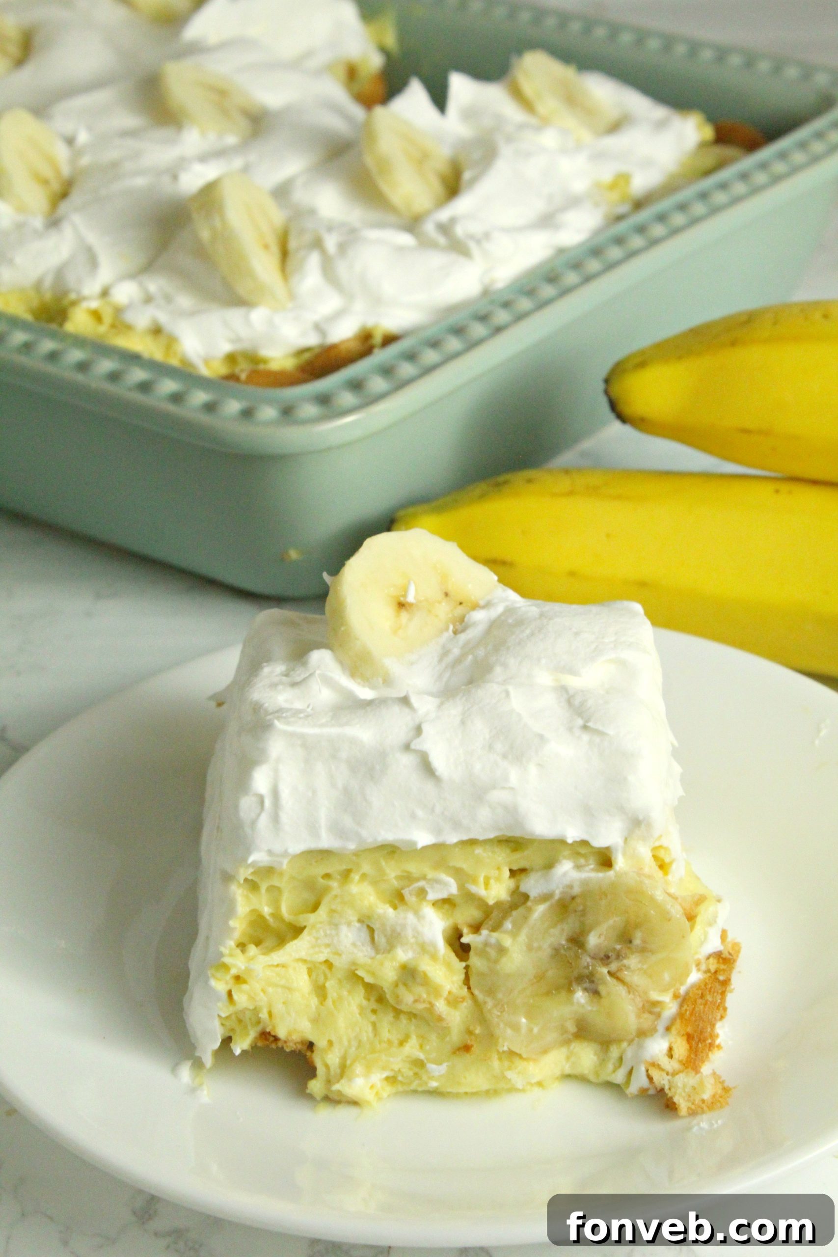 Simple Chilled Banana Pudding 13 A hand arranging fresh banana slices on top of the finished banana pudding before serving.